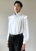 The Stacy Stewart Smith Poet Laureate Poet Laureate — a generously cut silk dress shirt with soft pleats, full-tucked sleeves, a crisp convertible collar with detachable neck jabot, and a samurai-inspired Kataginu shoulder. Romantic, dapper, and deliberately oversized in drape on a mannequin 6'3" with Stacy Stewart Smith onyx pigskin suede pleated Windsor pants and an alligator belt against a neutral background.
