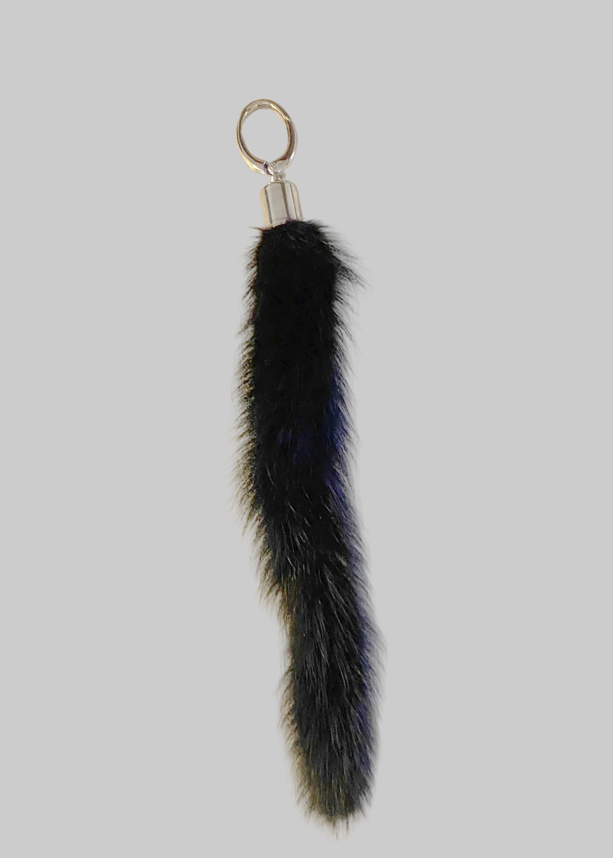 Black Gamma mink tail chrome topped keyring by Stacy Stewart Smith on an antique white surface