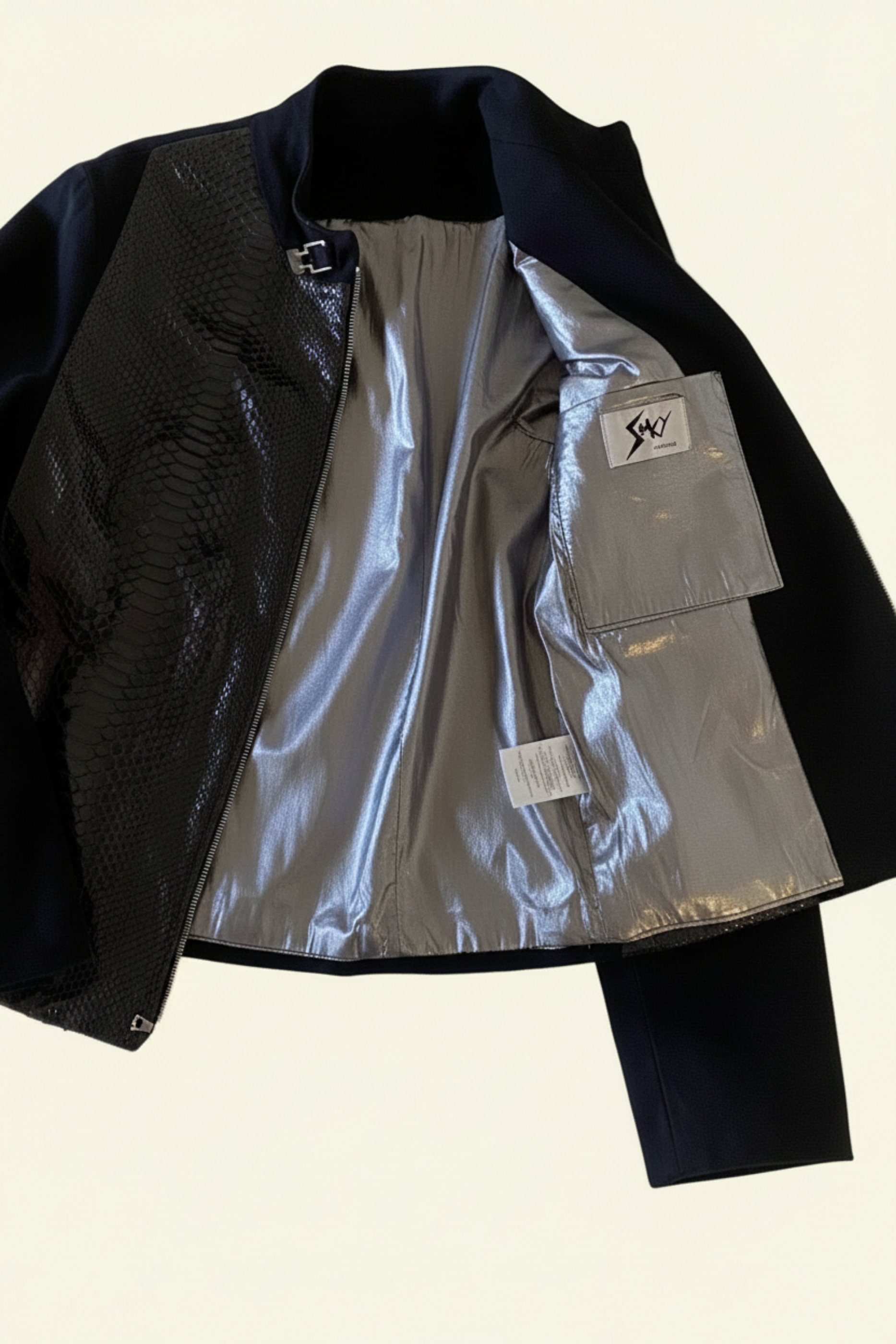 Stacy Stewart Smith Men's black Python & Denim Bellhop Jacket floating flat front view open gunmetal lame lining with antique white wall backdrop.