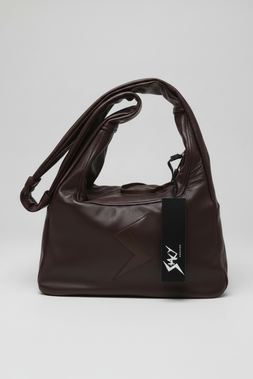 Stacy Stewart Smith Trapezoid Leather Messenger Bag in Espresso with the strap folded over the left top in front of a light gray backdrop.