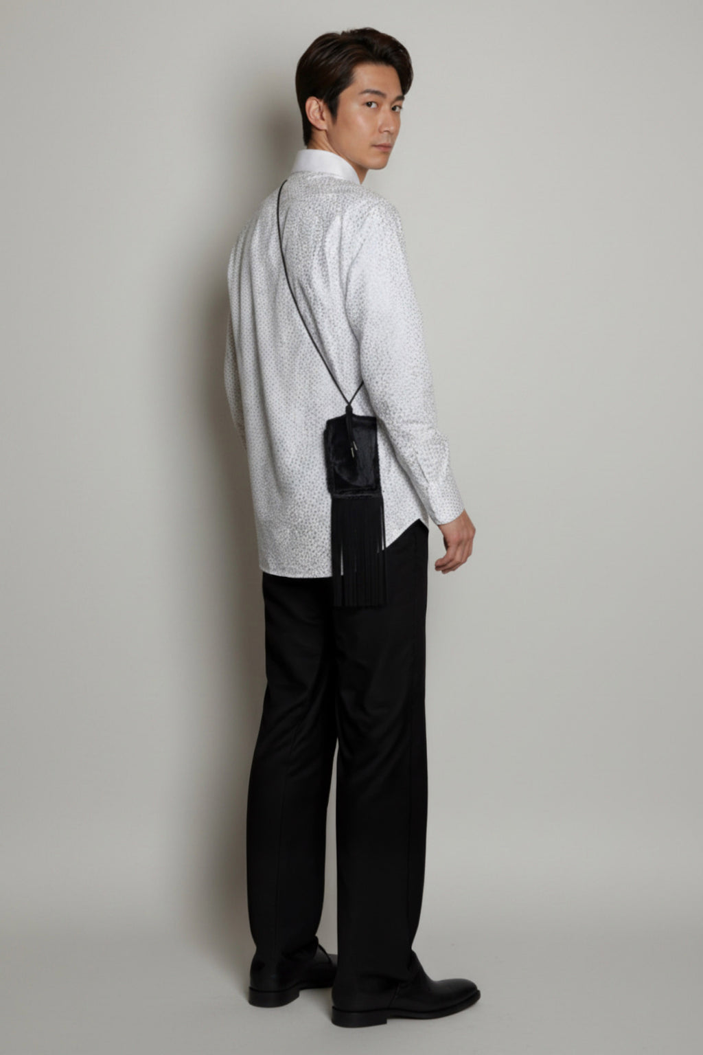 Stacy Stewart Smith Hair-On Calf Fringed Hope Wallet on a mannequin 6'3" turned from the back wearing a hand painted shirt by the designer and the wallet over the shoulder front view with gay background.