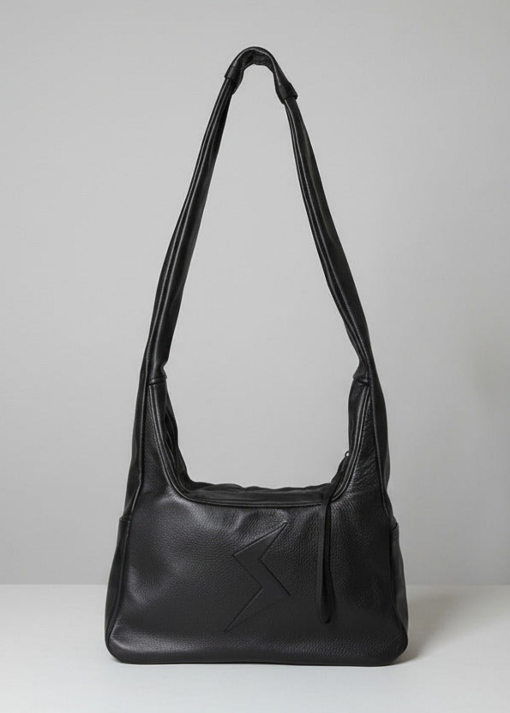 Stacy Stewart Smith Trapezoid Leather Messenger Bag in Onyx front view with the strap standing up in front of a light gray backdrop.