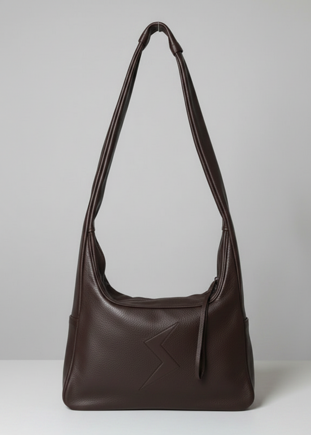 Stacy Stewart Smith Trapezoid Leather Messenger Bag in Espresso front view with the strap standing up in front of a light gray backdrop.