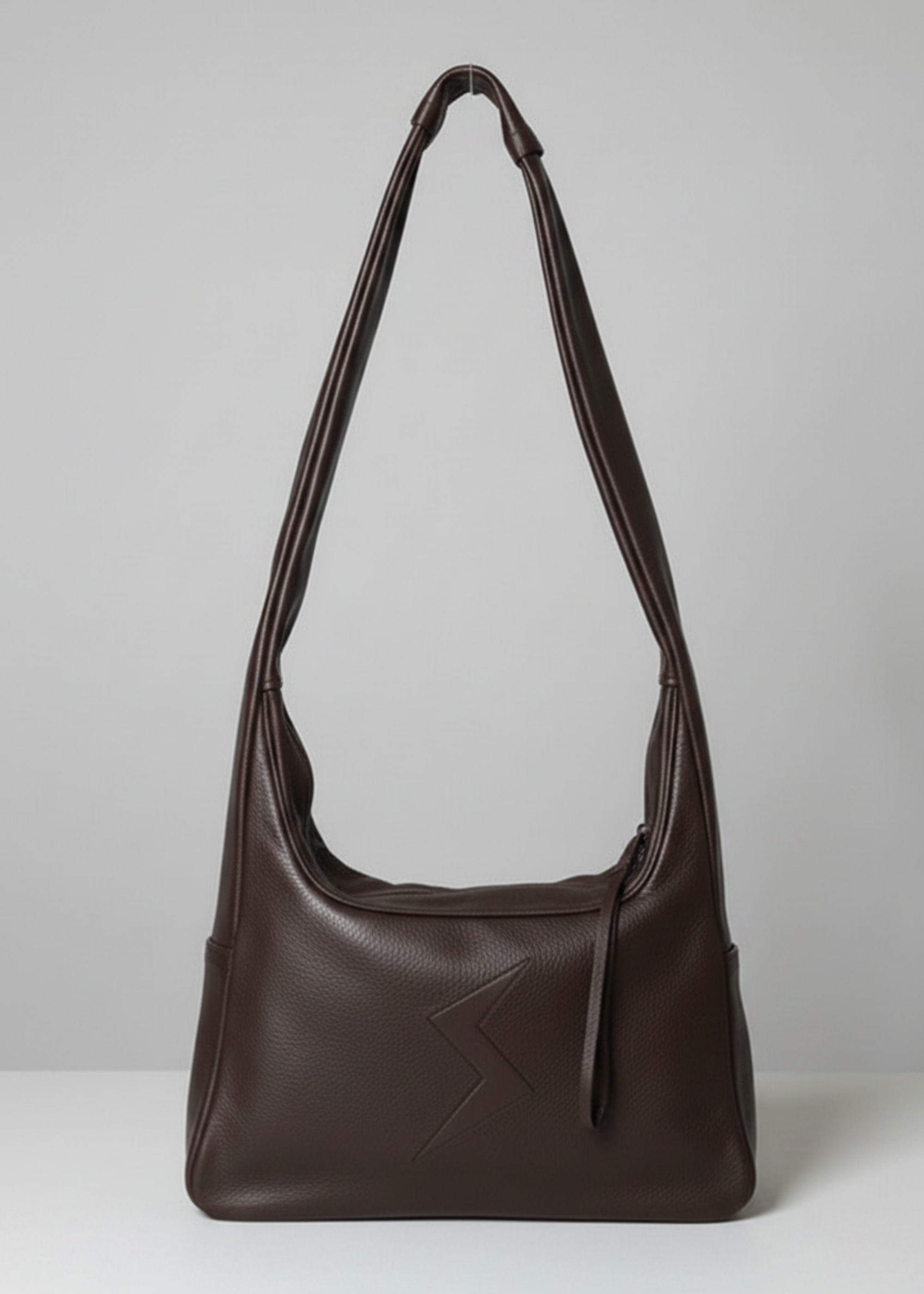 Stacy Stewart Smith Trapezoid Leather Messenger Bag in Espresso front view with the strap standing up in front of a light gray backdrop.