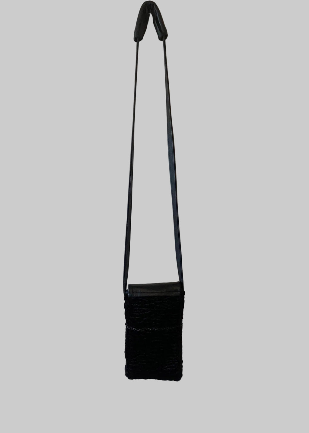Stacy Stewart Smith Onyx Persian lamb and leather Pocket Messenger bag with a strap back view hanging on a gray background