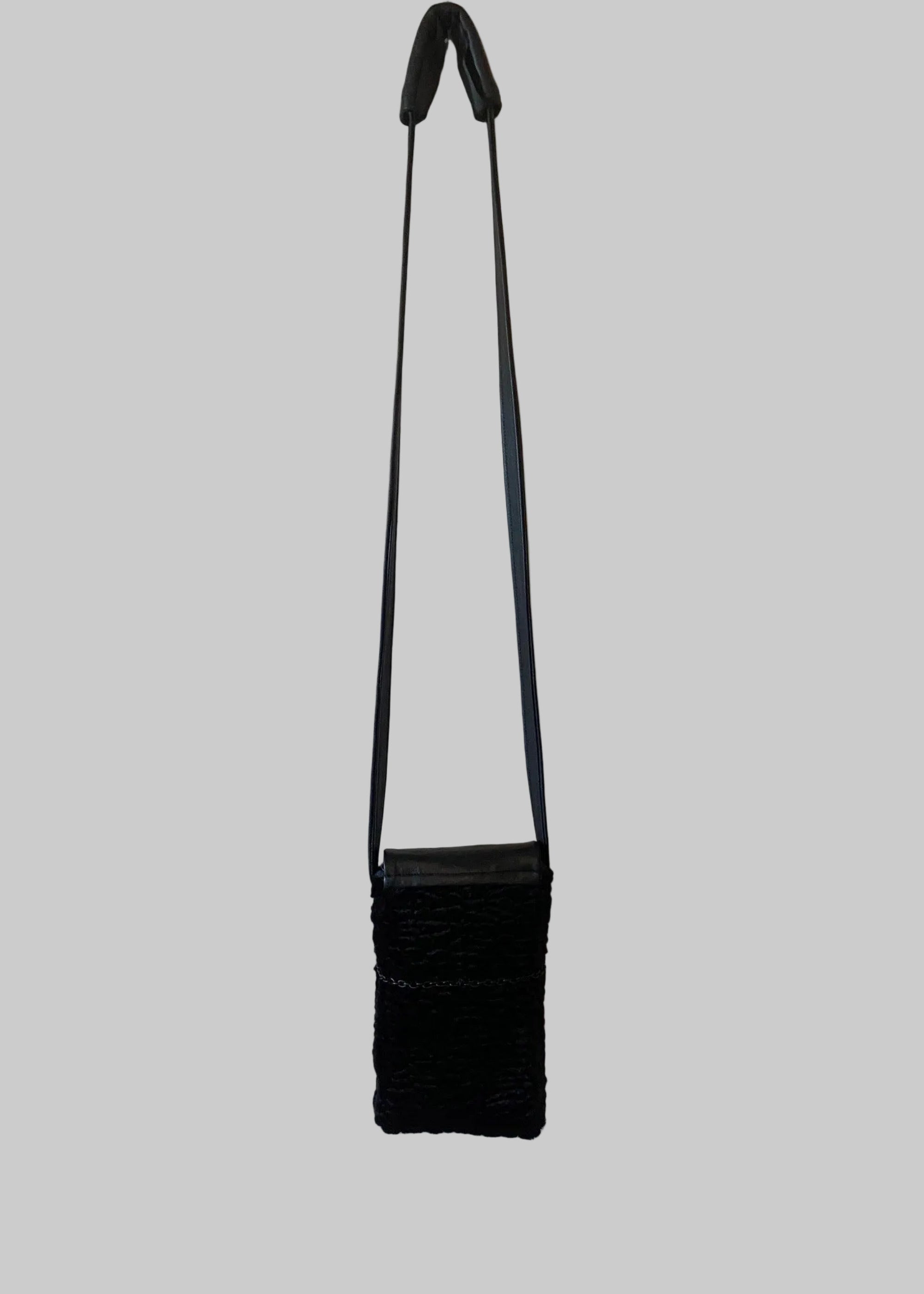 Stacy Stewart Smith Onyx Persian lamb and leather Pocket Messenger bag with a strap back view hanging on a gray background