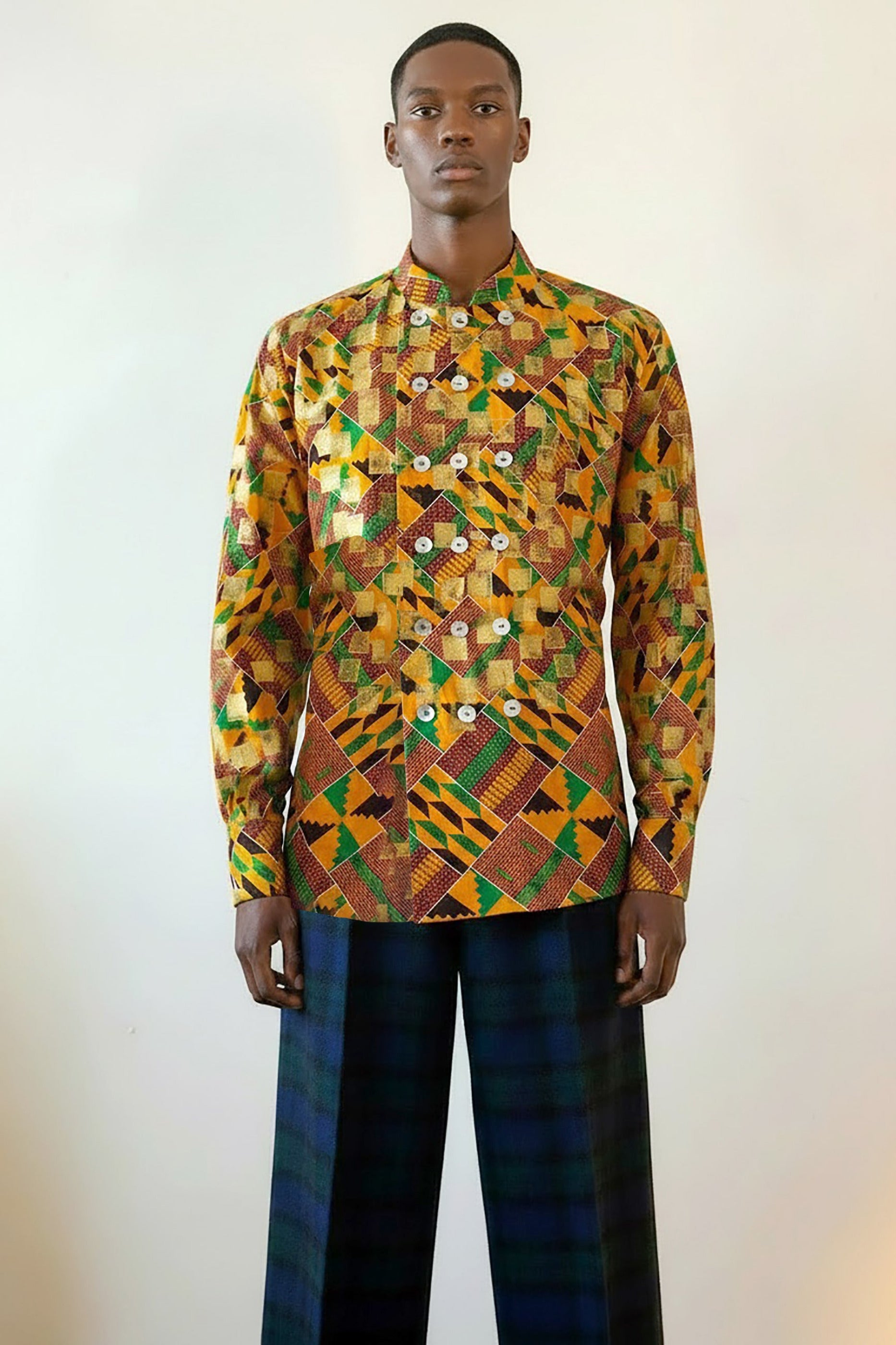 Stacy Stewart Smith's Noble Kente long-sleeve button-up premium cotton Kente cloth dress shirt with manadarin collar, long sleeve gold metallic hand pixel over-printing real shell buttons displayed on a male model torso front view against a plain wall.
