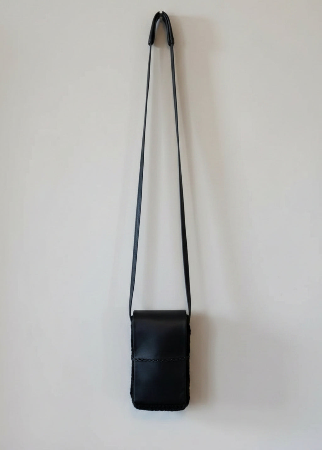Stacy Stewart Smith Onyx Persian lamb and leather Pocket Messenger  bag with a strap hanging on a gray background