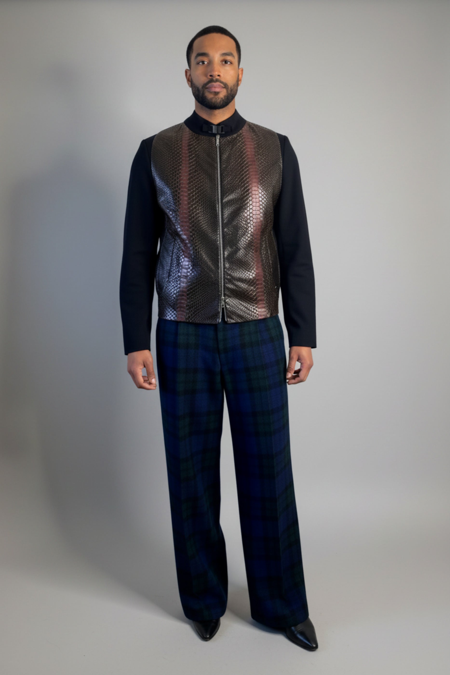 Stacy Stewart Smith's Python & Denim Bellhop Jacket with Blackwatch Plaid Harris Tweed Reality Pants on male model 6'3" against a white wall with a wooden floor. 