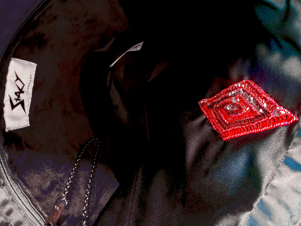 Interior view of Stacy Stewart Smith's Lagoon Blue Chenille Dragon & Ruby Tote shows black suede zip pocket, pull chain red, sequin & beaded rhombus appliqué and Stacy Couture brand label.