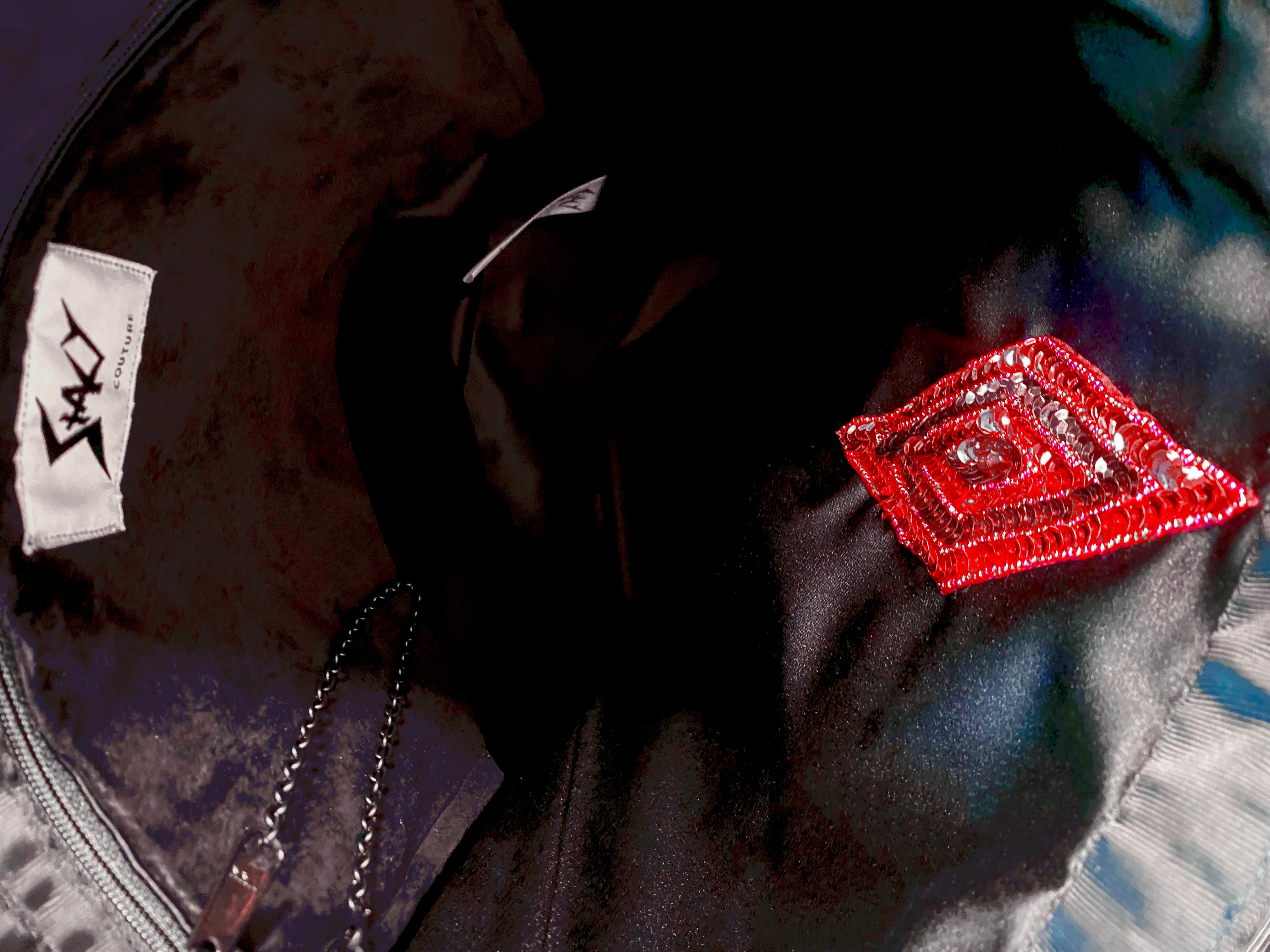 Interior view of Stacy Stewart Smith's Lagoon Blue Chenille Dragon & Ruby Tote shows black suede zip pocket, pull chain red, sequin & beaded rhombus appliqué and Stacy Couture brand label.