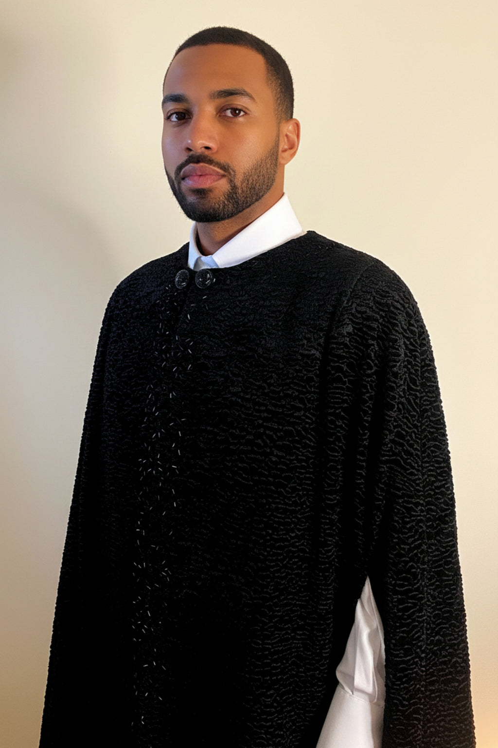 The Grand Soir Palace Cape by Stacy  Stewart Smith is cut for exactly that moment — a structured sweep of flowing black Persian lamb on a mannequin 6'3" against an ivory backdrop. Front view zoomed-in with  cape closed to show bugle beading, ornate double glass button closure and one arm through front elbow slit.