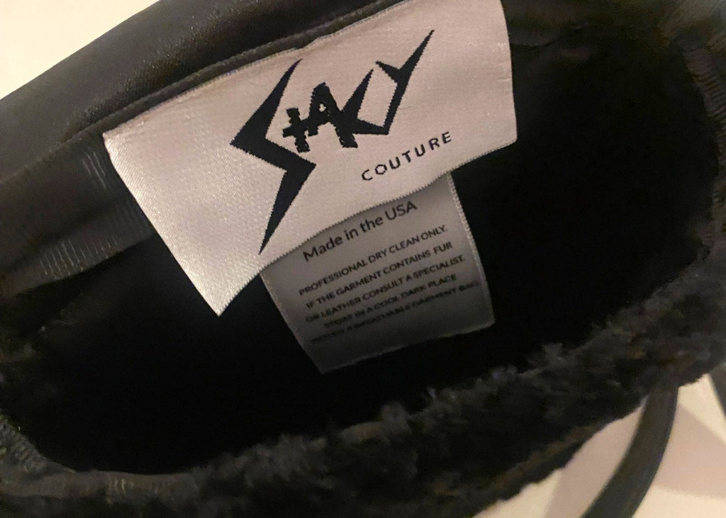 Stacy Stewart Smith Onyx Persian lamb and leather Pocket Messenger  bag interior with brand label showingwith a strap hanging on a gray background