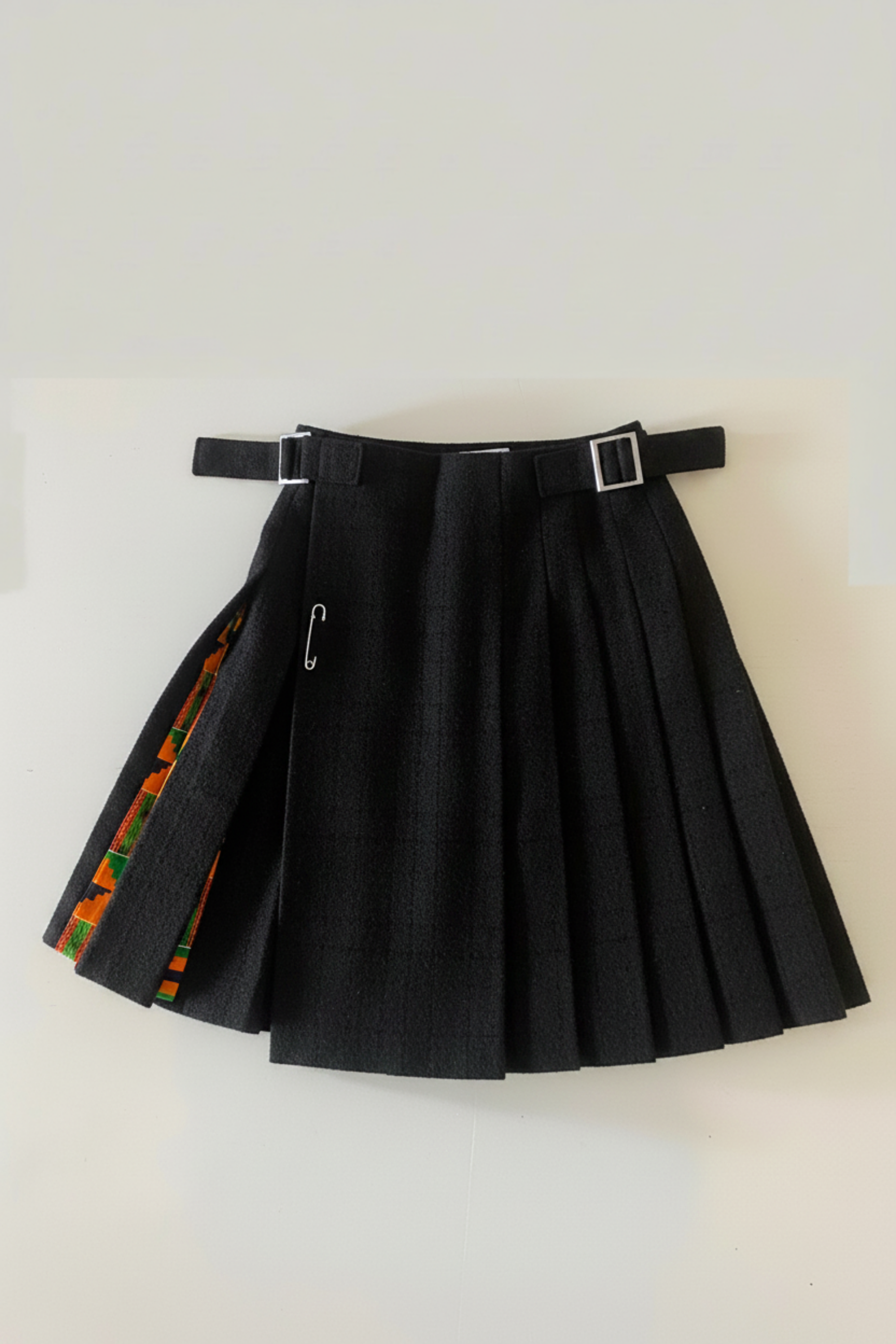 Stacy  Stewart Smith men's Black Harris Tweed© Reality Kilt has Kente cloth inlays, chrome side adjustable buckles and kilt flat against a plain light surface.