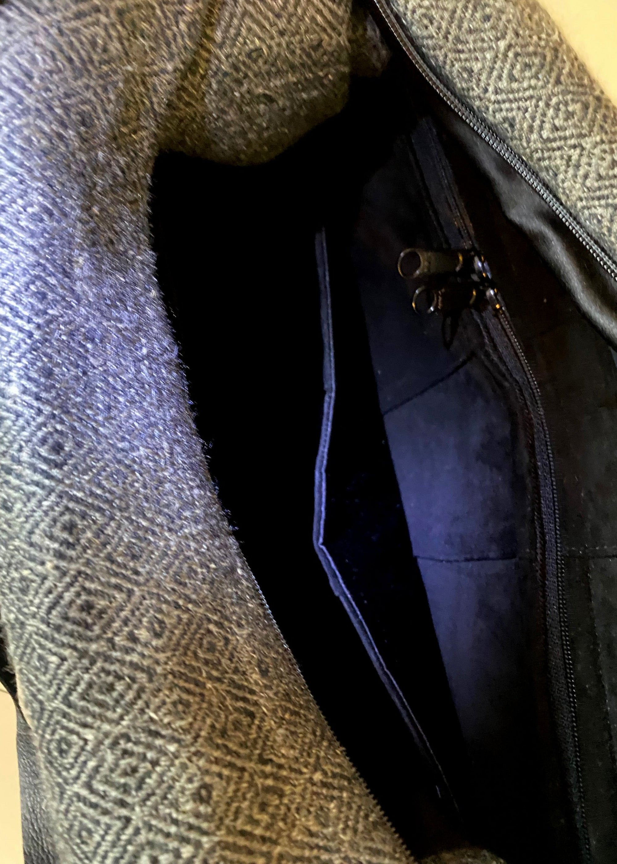 Stacy Stewart Smith's Men's Diamond Dodger Trapezoid messenger bag in Cement/Onyx inside onyx suede lining  view showing zip pocket and divider against a gray background.