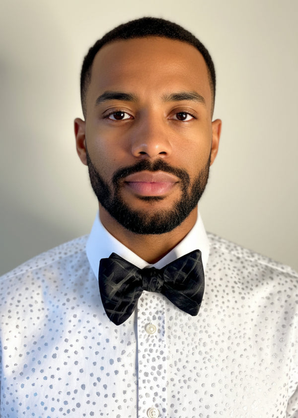 Mannequin wearing a hand-painted shirt with a black hand-painted plaid bow tie, both by Stacy Stewart Smith, against a neutral background