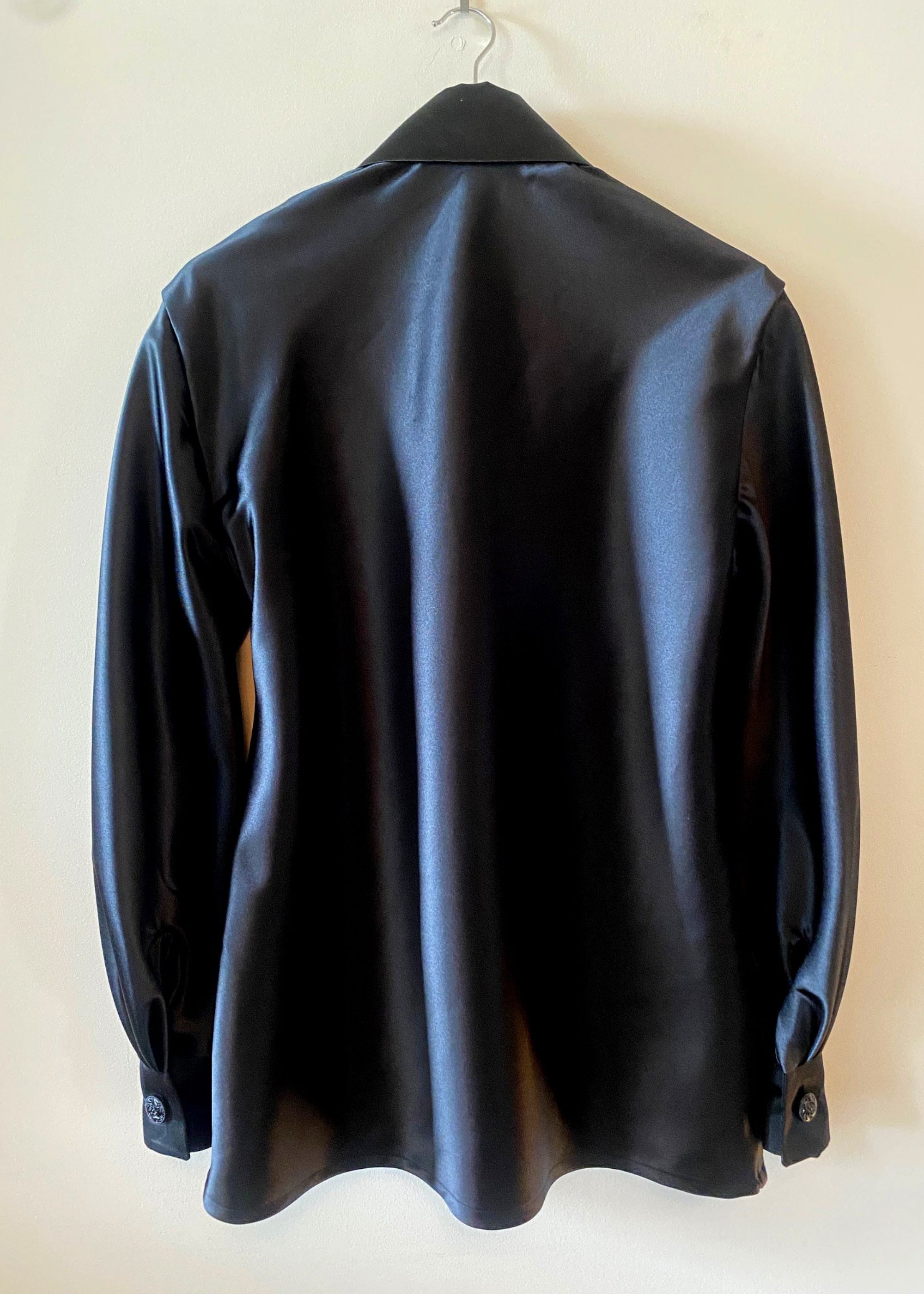 Stacy Stewart Smith Men's Onyx Duex Fois Silk Satin Shirt on a hanger back view hanging against an antique white wall.