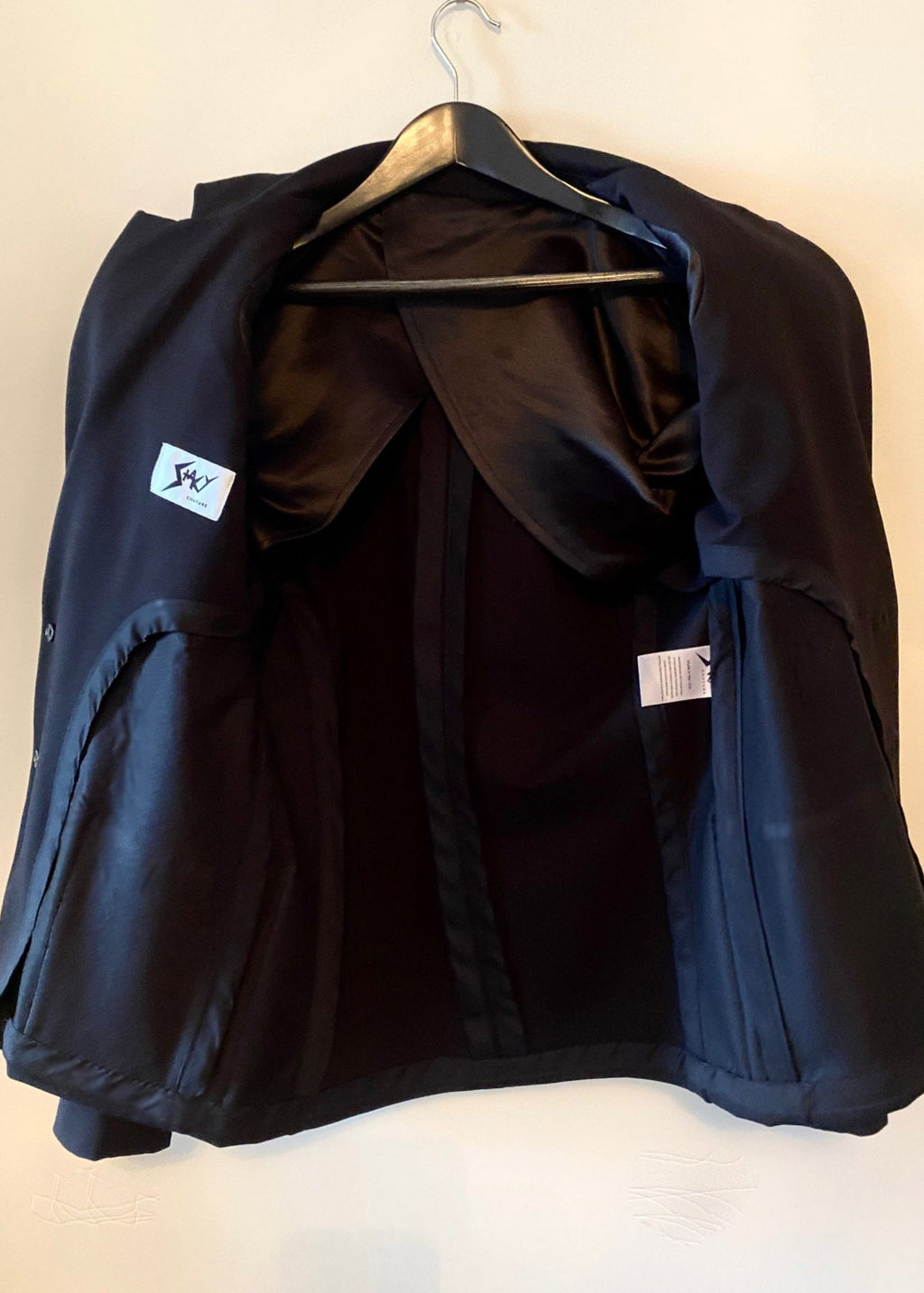 Stacy Stewart Smith Men's Black Knit, Sequin and Beaded Harlequin Blazer front view open exposing half lining and house brands on a hanger with antique white wall.