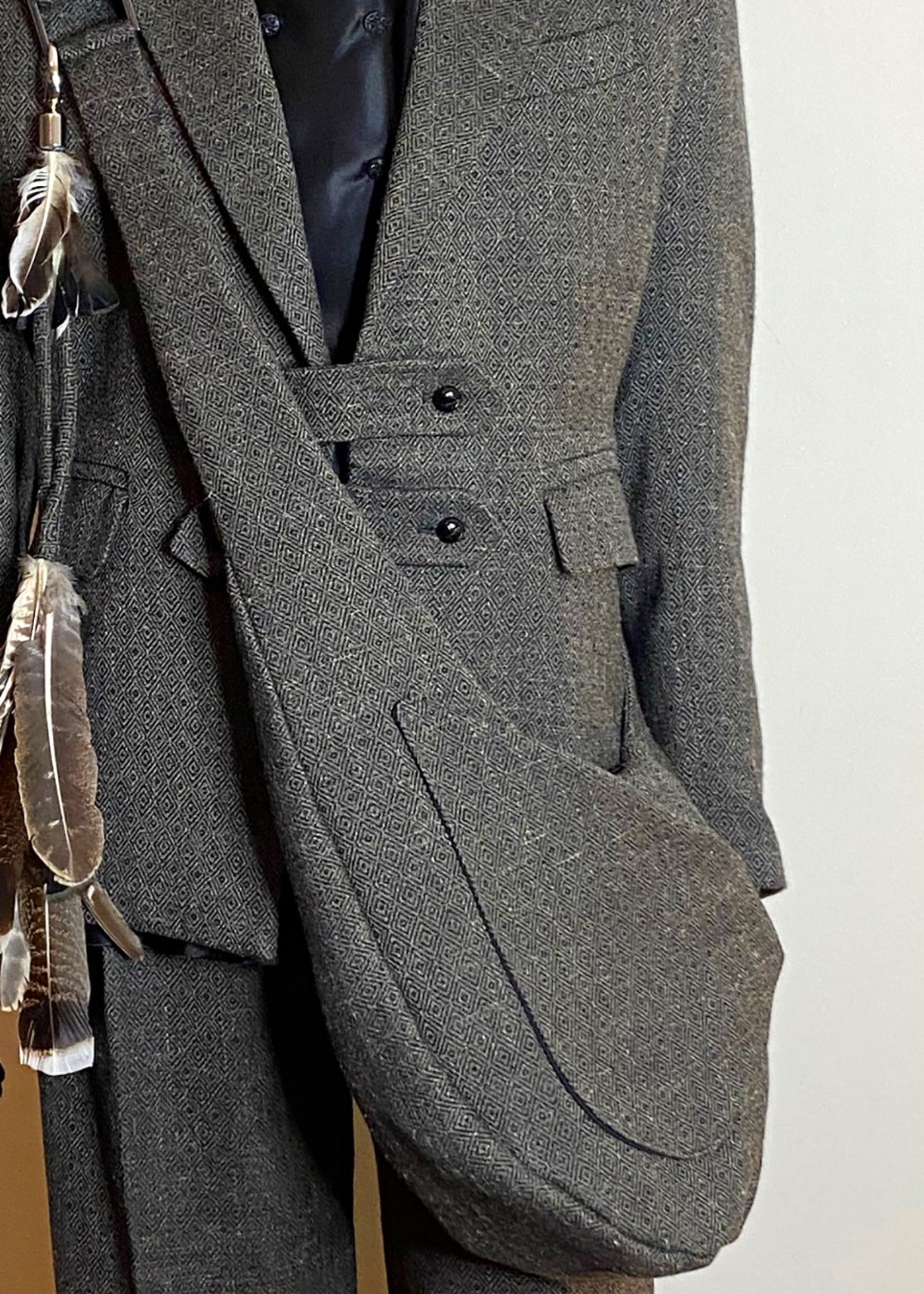 Stacy Stewart Smith Men's Diamond Dodger Tweed Newsie Sling Bag on male model 6'3" wearing matching tweed suit in front of an an Ivory wall. 