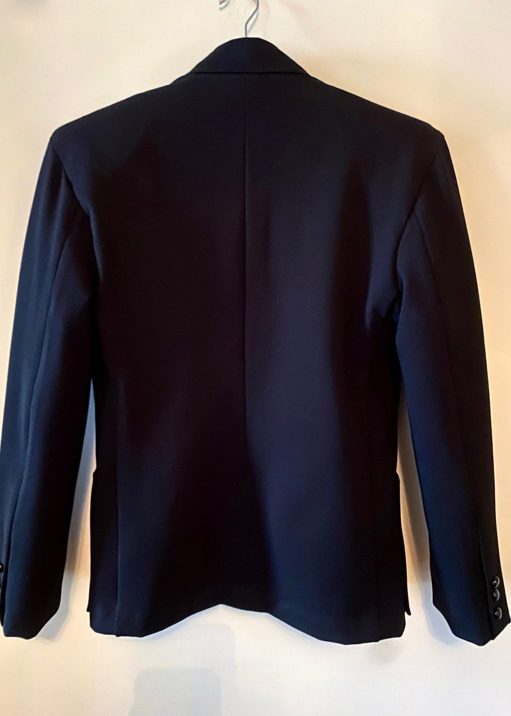 Stacy Stewart Smith Men's Black Knit, Sequin and Beaded Harlequin Blazer back view on a hanger with antique white wall.