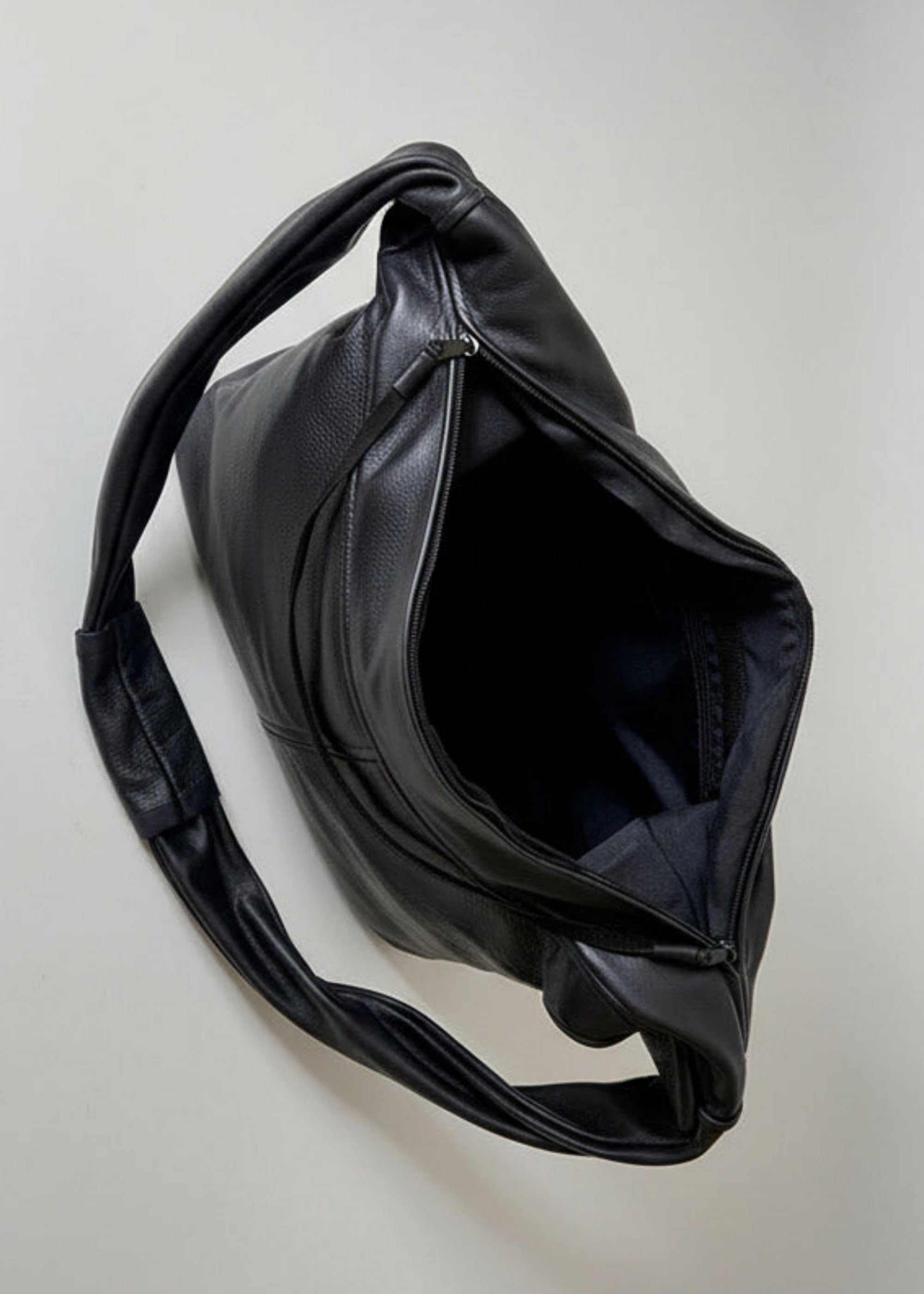 Stacy Stewart Smith Trapezoid Leather Messenger Bag in Onyx view of the unzipped top in front of a light gray backdrop.