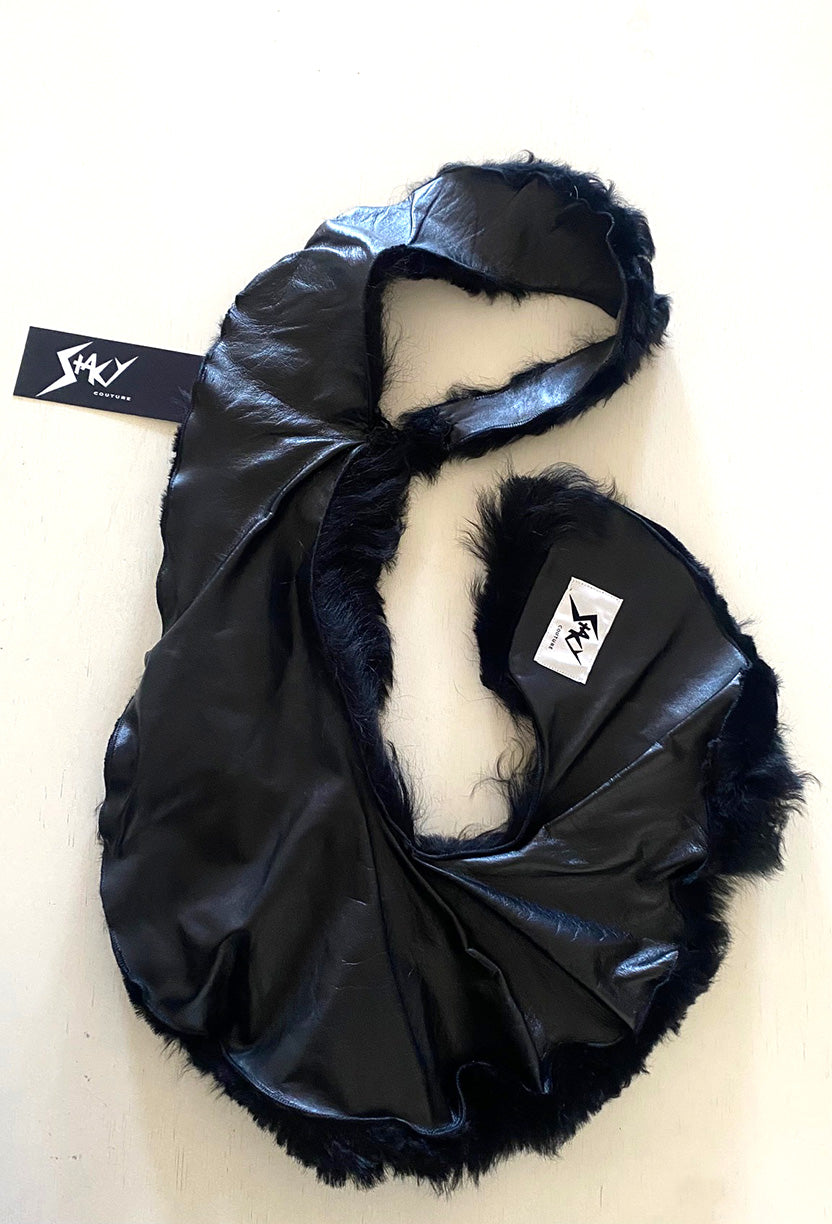 Stacy Stewart Smith Black Shearling & Leather Coil Scarf leather side flat on a white surface with brand hang tag and label.