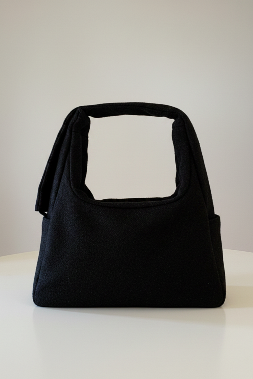 Stacy Stewart Smith's Men's Onyx Harris Tweed® Trapezoid messenger bag with  the shoulder strap folded back view against a gray background.