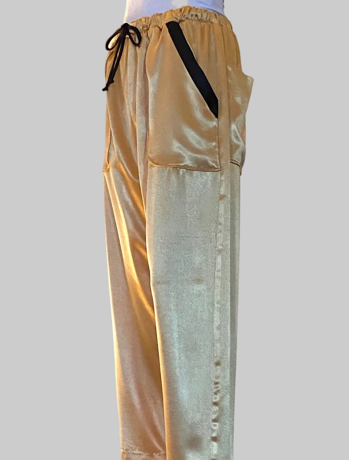 Stacy Stewart Smith men's gold satin pants with a black drawstring on a light background