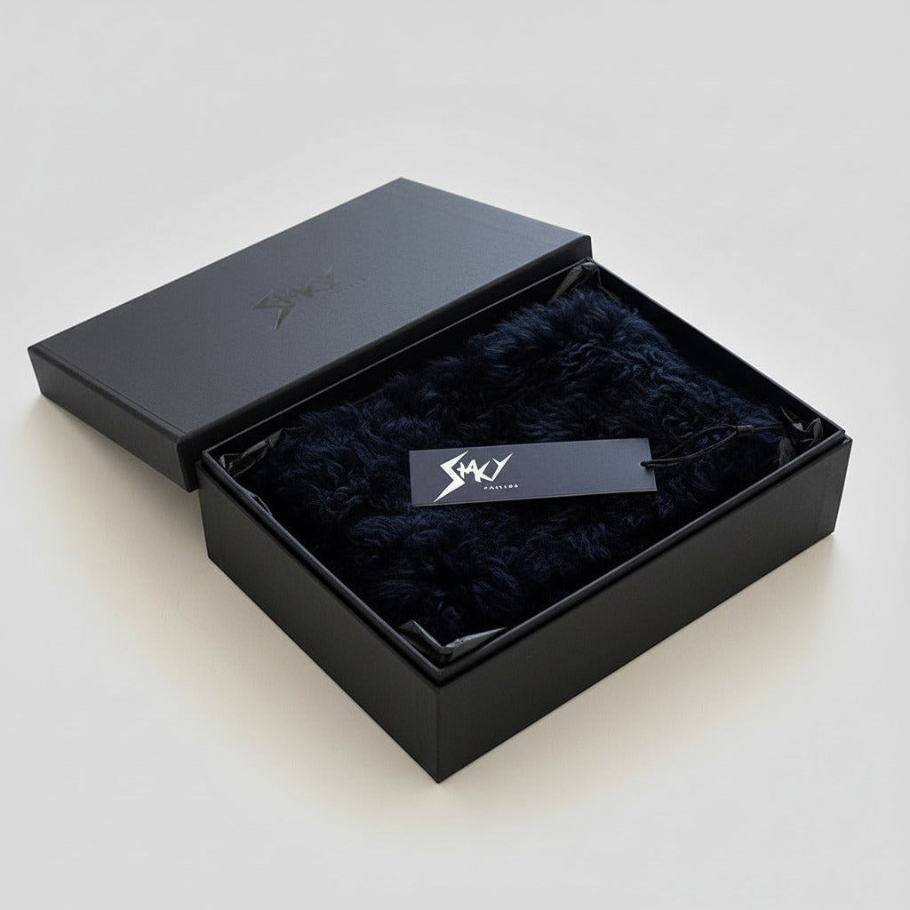 Stacy Stewart Smith Black Shearling & Leather Coil Scarf fur side in a black gift box on a white surface.