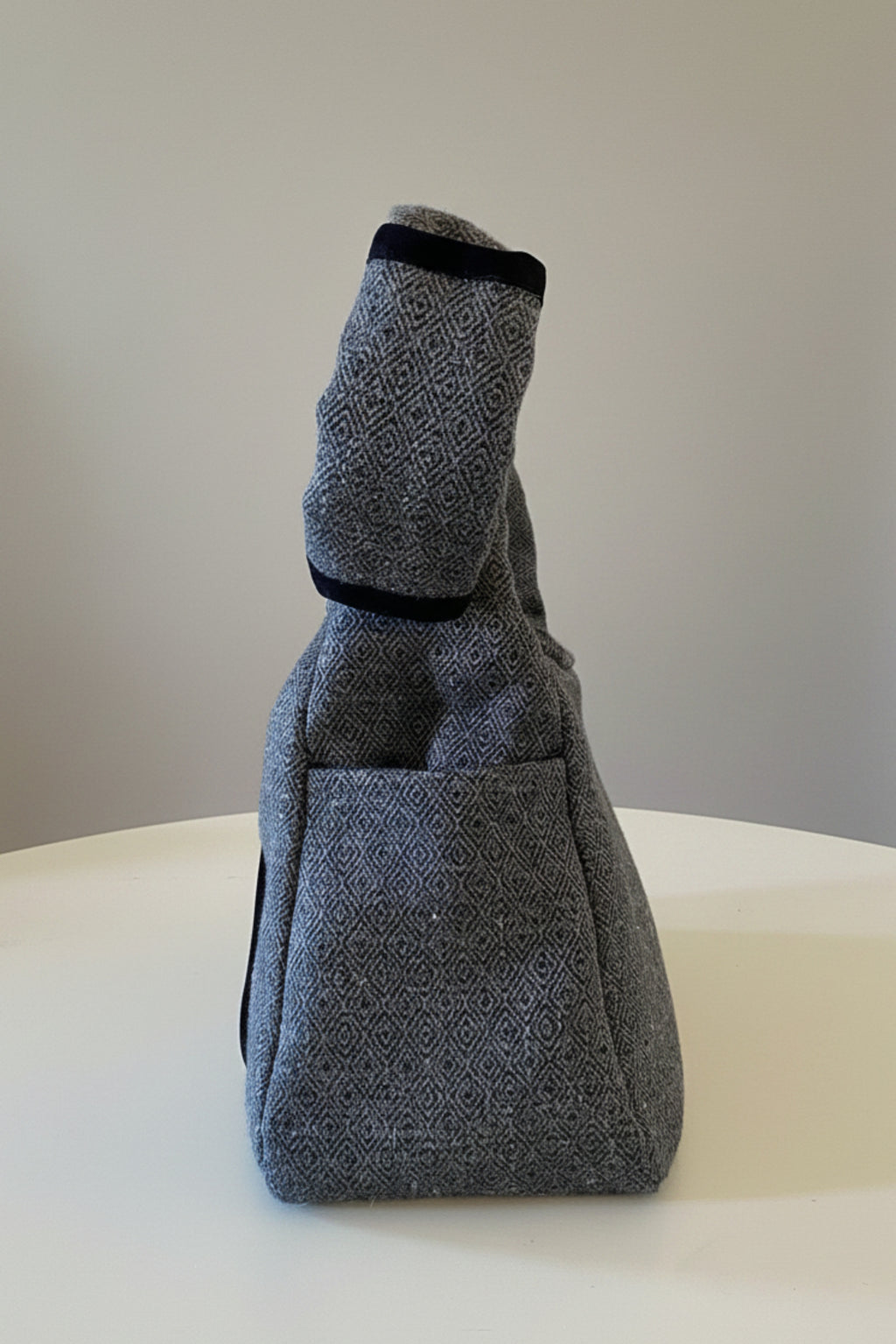 Stacy Stewart Smith's Men's Diamond Dodger Trapezoid messenger bag in Cement/Onyx inside onyx side view showing shoulder rest against a gray background.