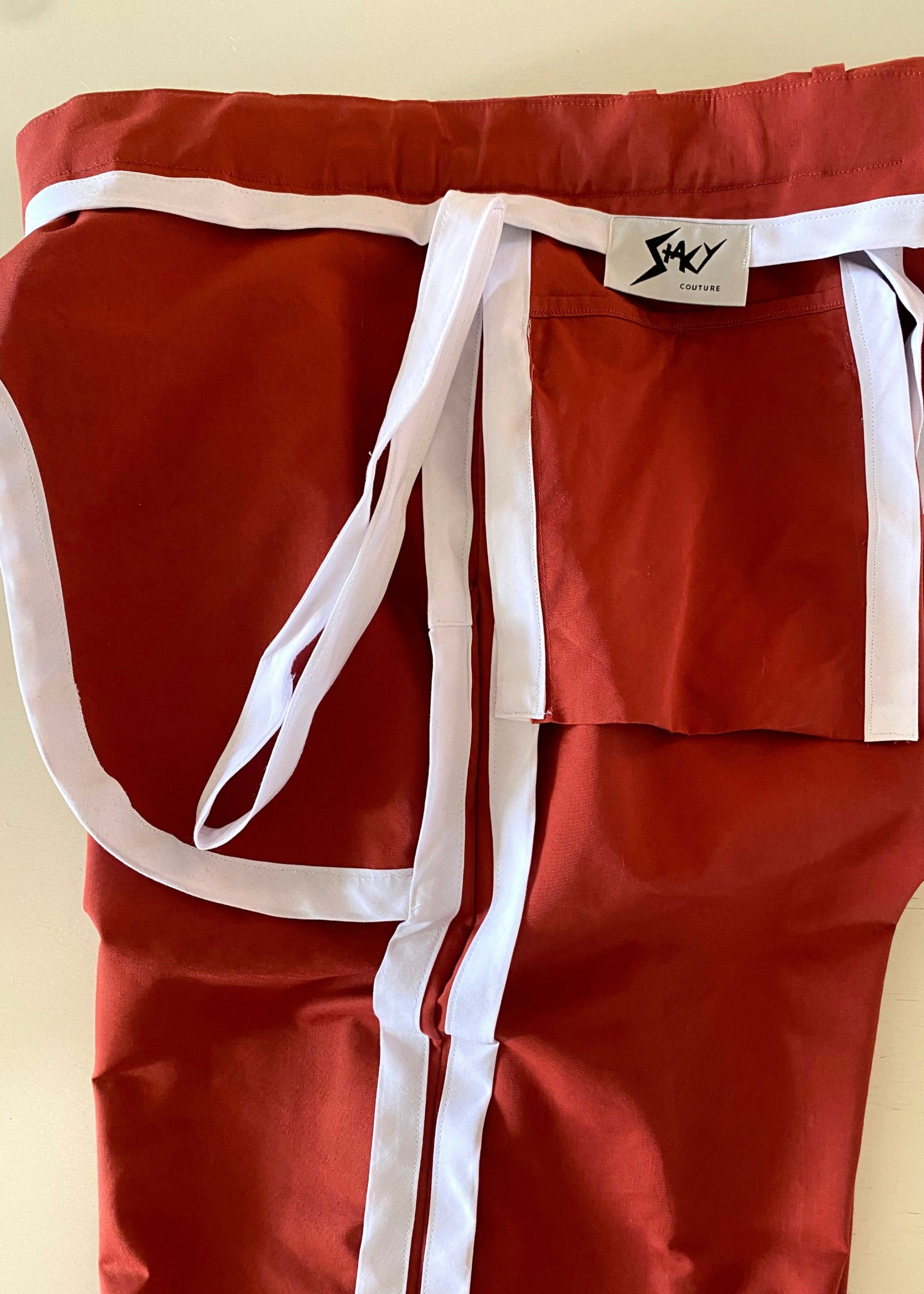 Stacy Stewart Smith Dragon & Ruby Flat Front Persimmon Cotton Twill Windsor Pants flat inside detail view on an ivory surface.