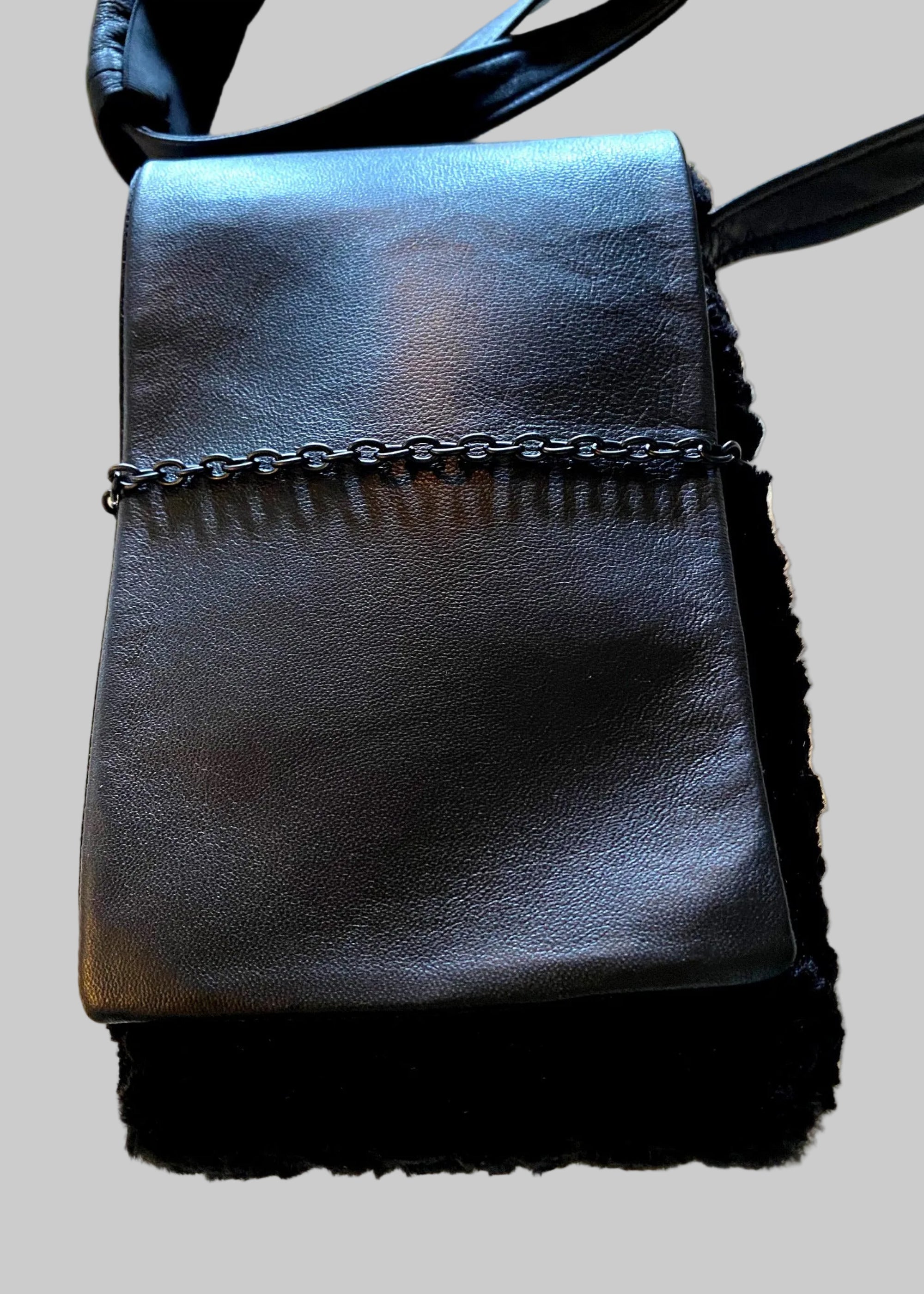 Stacy Stewart Smith Onyx Persian lamb and leather Pocket Messenger  bag with a strap cropped front view on a gray surface.