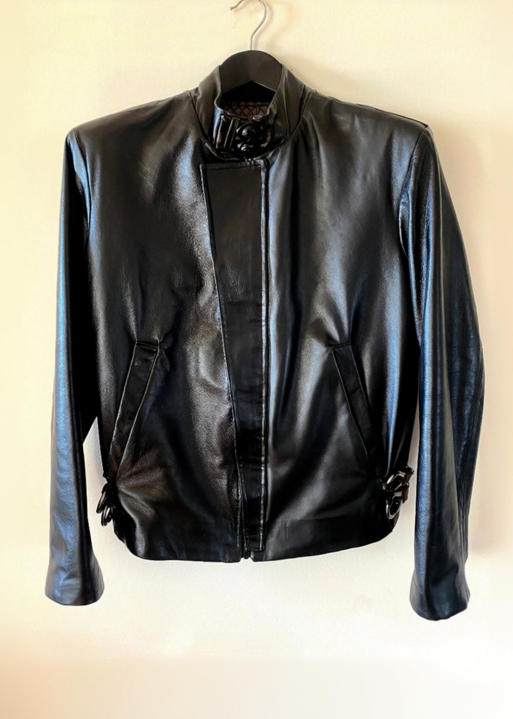 Stacy Stewart Smith Men's Onyx Flange-Back Leather Moto Jacket hanging front view against an antique white background.