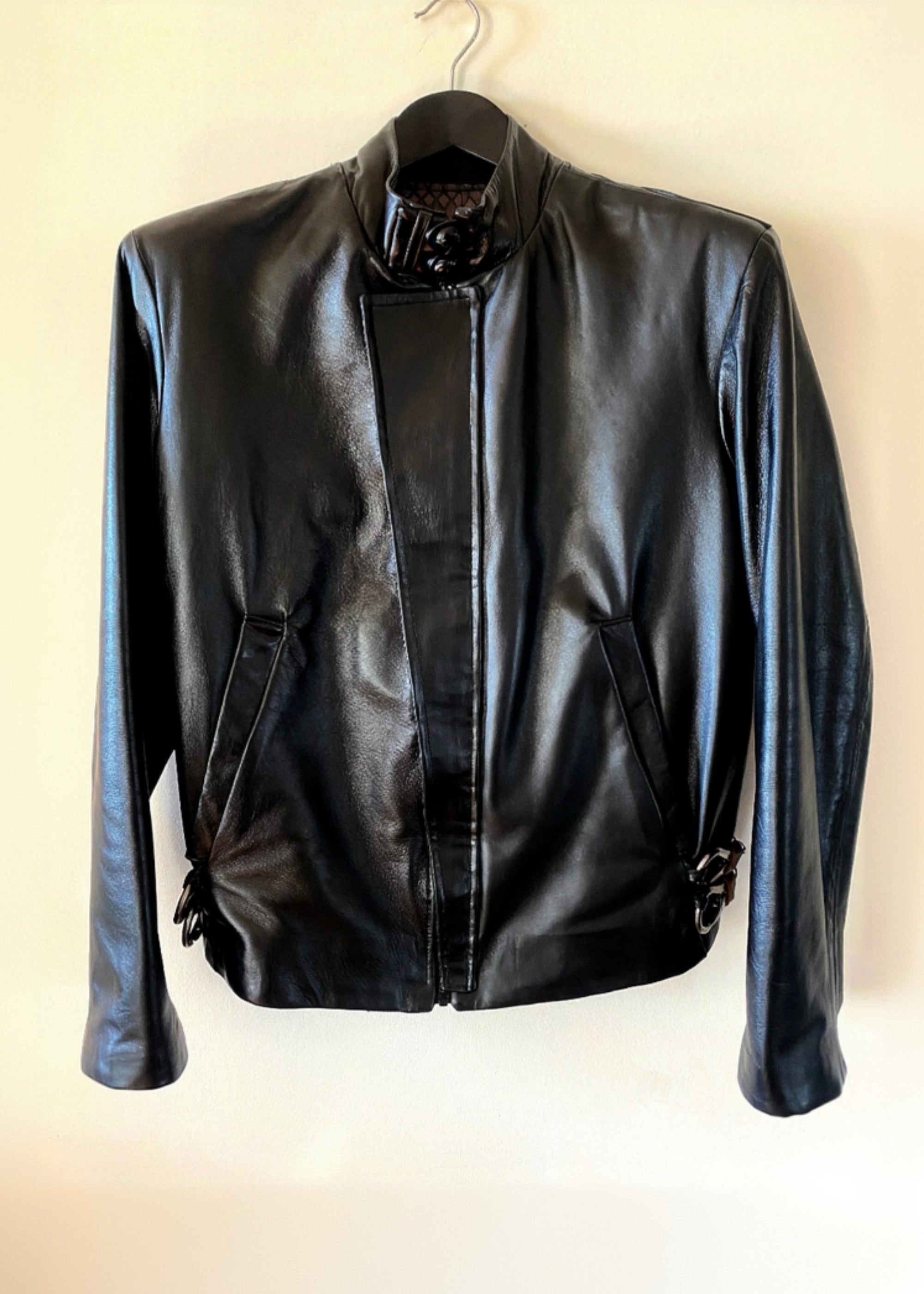 Stacy Stewart Smith Men's Onyx Flange-Back Leather Moto Jacket hanging front view against an antique white background.