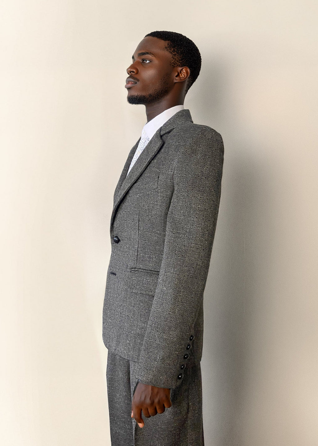 Stacy Stewart Smith Men's Diamond Dodger Tweed Notched Lapel Blazer on a mannequin 6'3" (side view) against an Antique White wall with a Stacy Stewart Smith oil painting hanging.