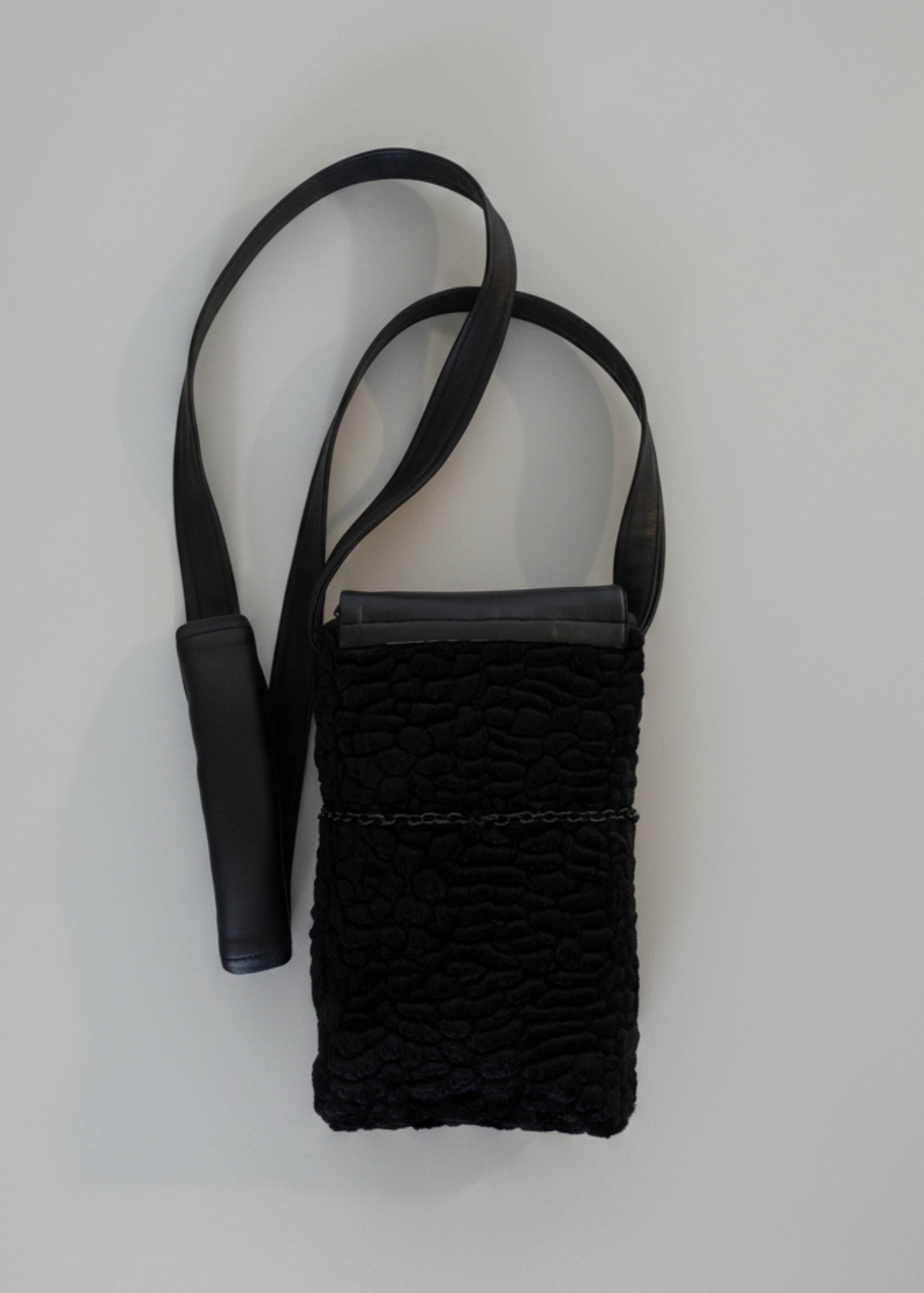 Stacy Stewart Smith Onyx Persian lamb and leather Pocket Messenger bag back view flat with a strap on a gray surface.