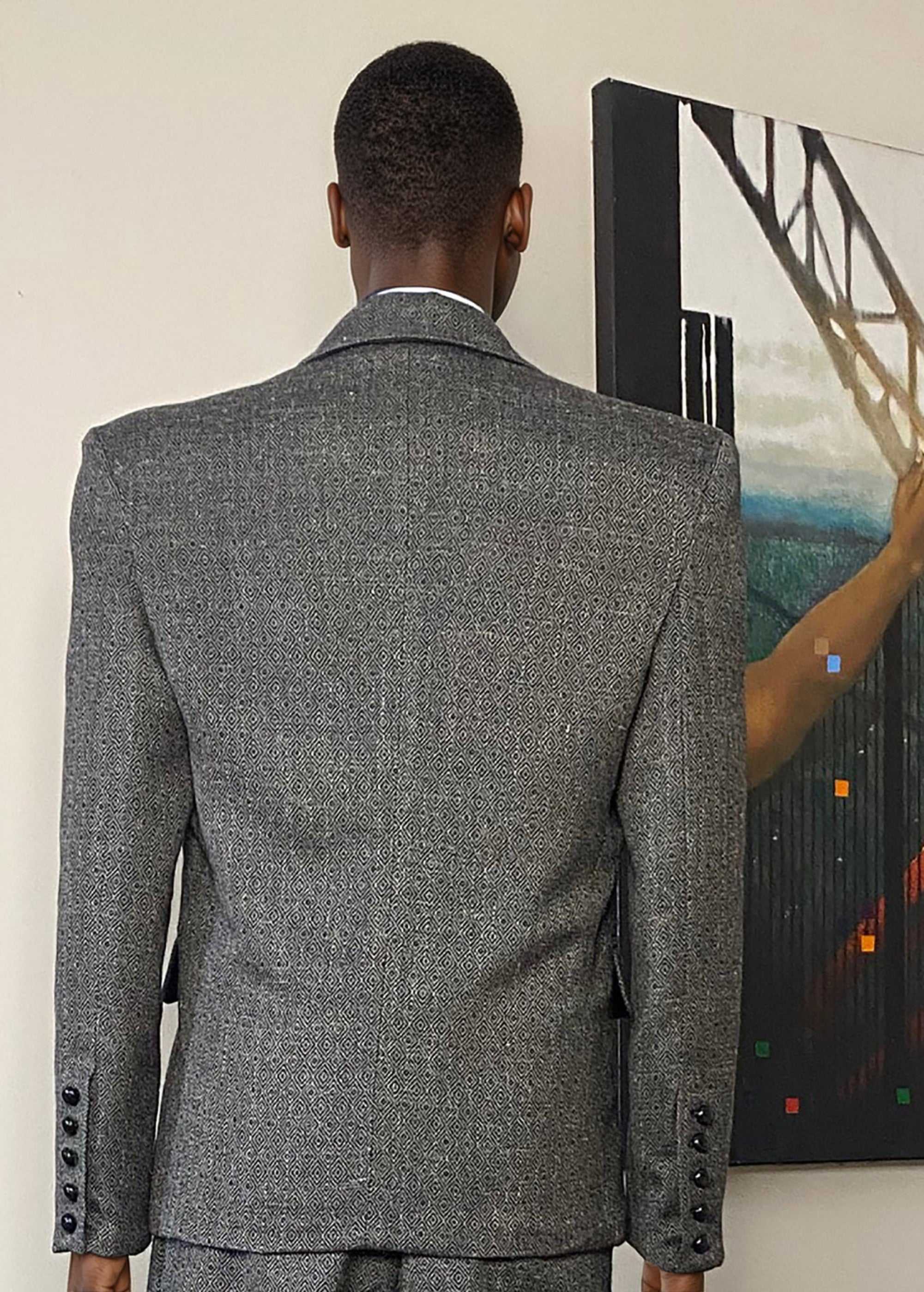 Stacy Stewart Smith Men's Diamond Dodger Tweed Notched Lapel Blazer on a mannequin 6'3" (back view) against an Antique White wall with a Stacy Stewart Smith oil painting hanging.