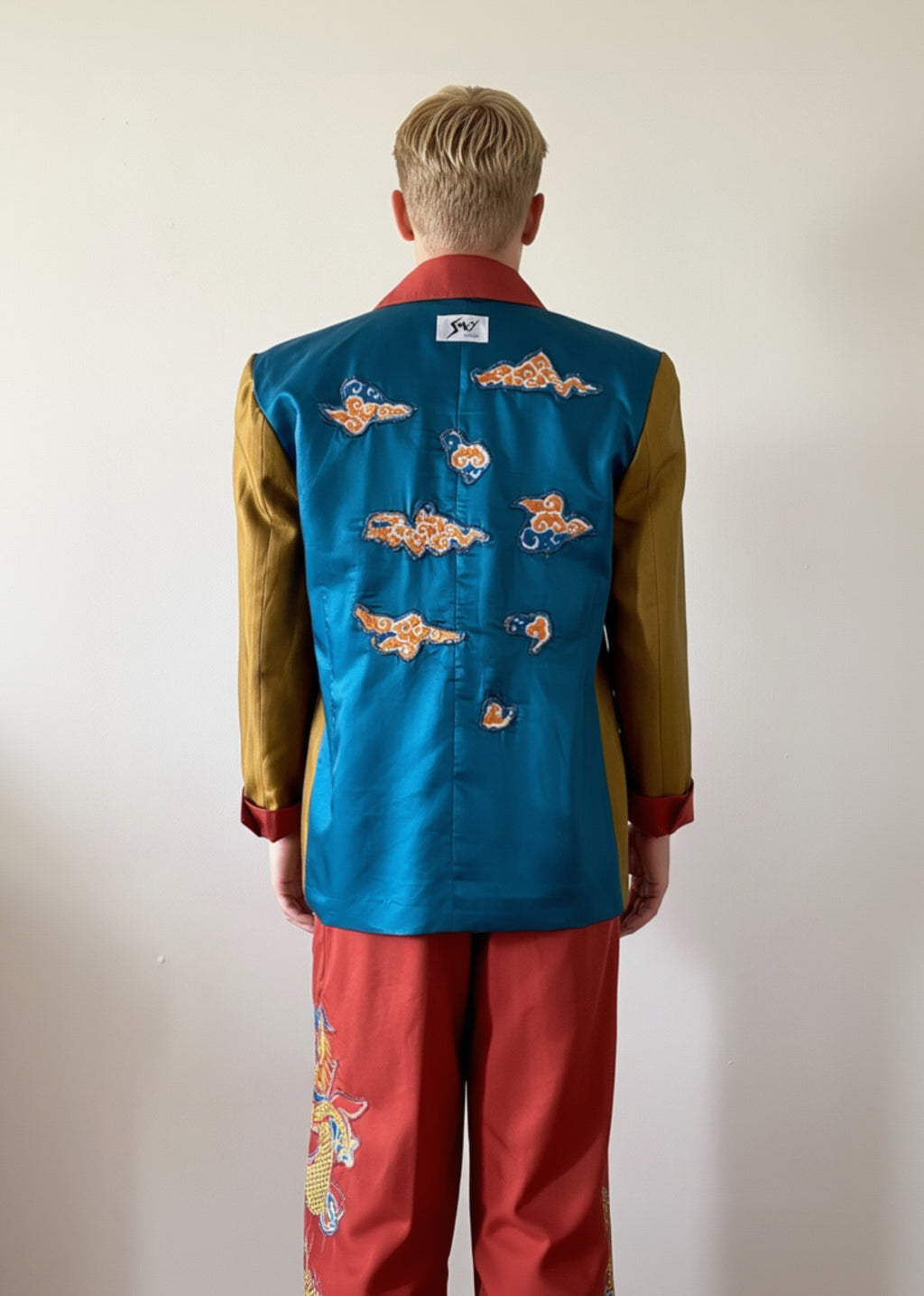 Sky & Ruby Trench-Jack unbelted back lining view showing tapestry appliqué and brand label on  mannequin 6'3" in front of an antique white wall.