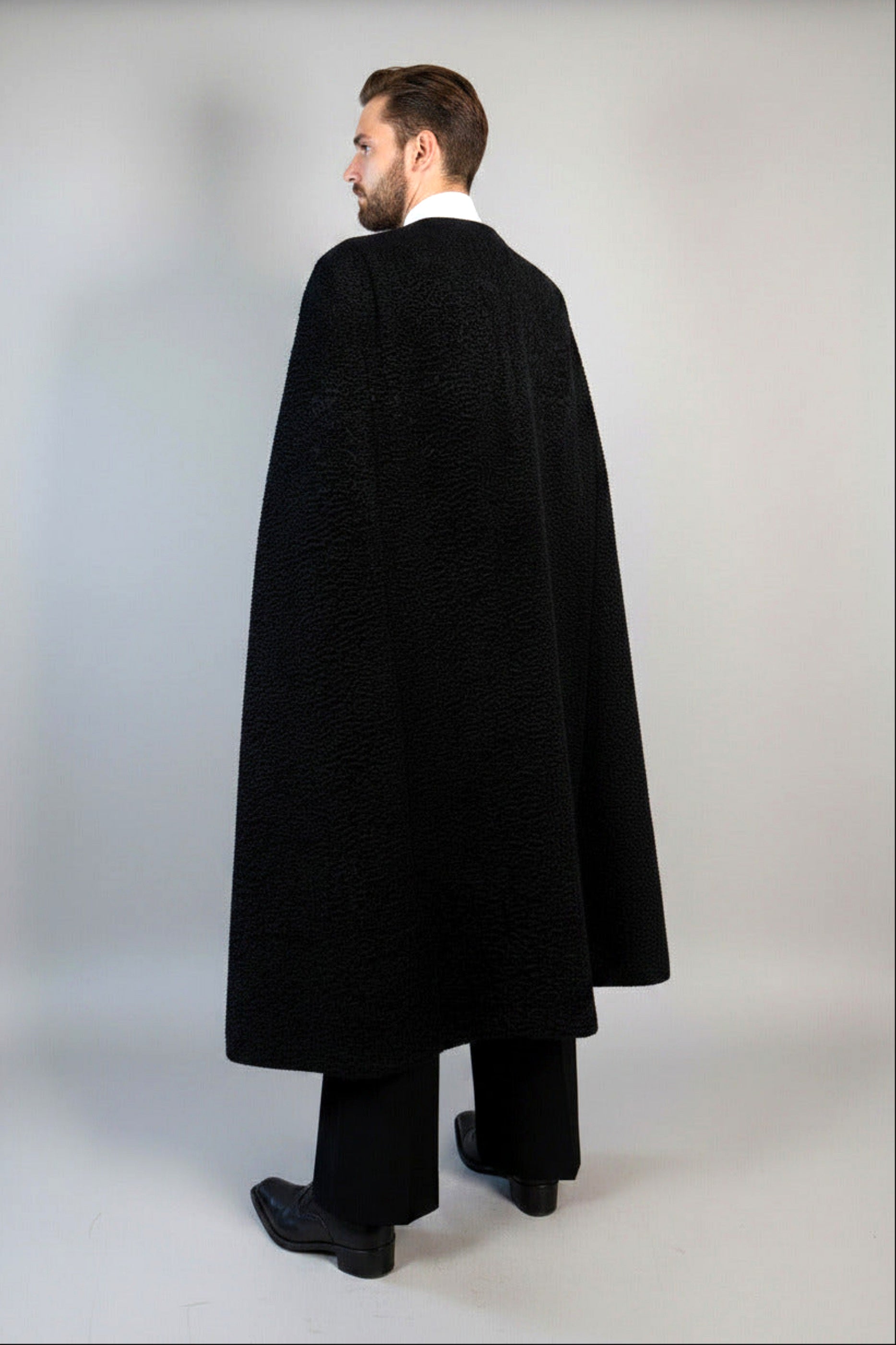 The Grand Soir Palace Cape by Stacy  Stewart Smith is cut for exactly that moment — a structured sweep of flowing black Persian lamb on a mannequin 6'3" against a gray backdrop. Front back view with cape closed.