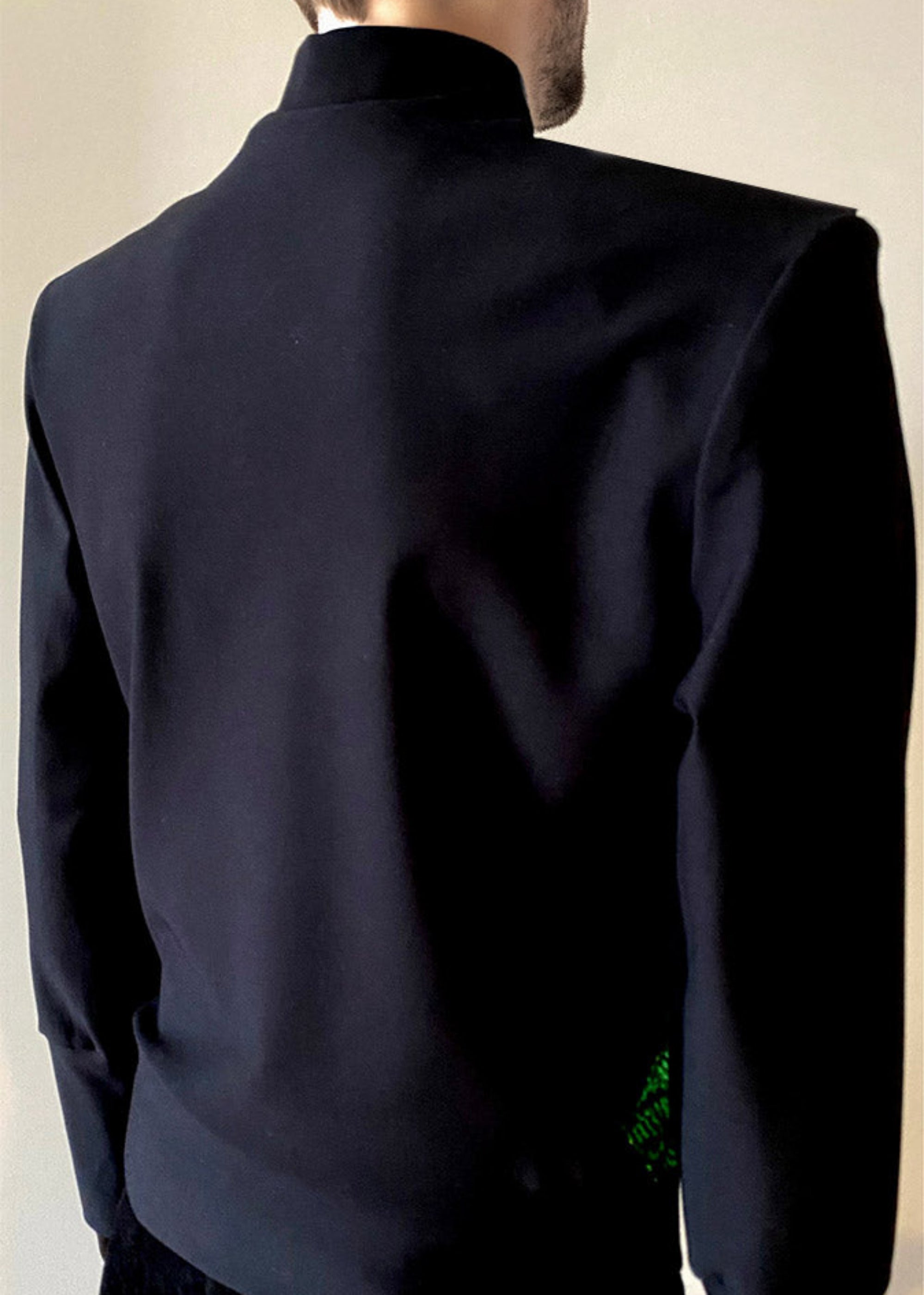 Back view mannequin 6'3" wearing a Stacy Stewart Smith Men's Argyle Labyrinth Peridot and Black Sequined Knit Top with black pants against a Antique White wall.