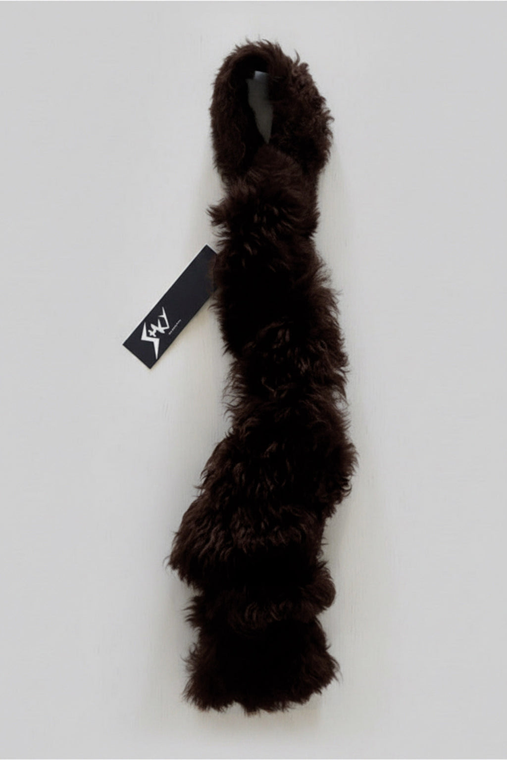 Stacy Stewart Smith Espresso Shearling & Leather Coil Scarf fur side with Stacy Couture hang tag against gray backdrop.