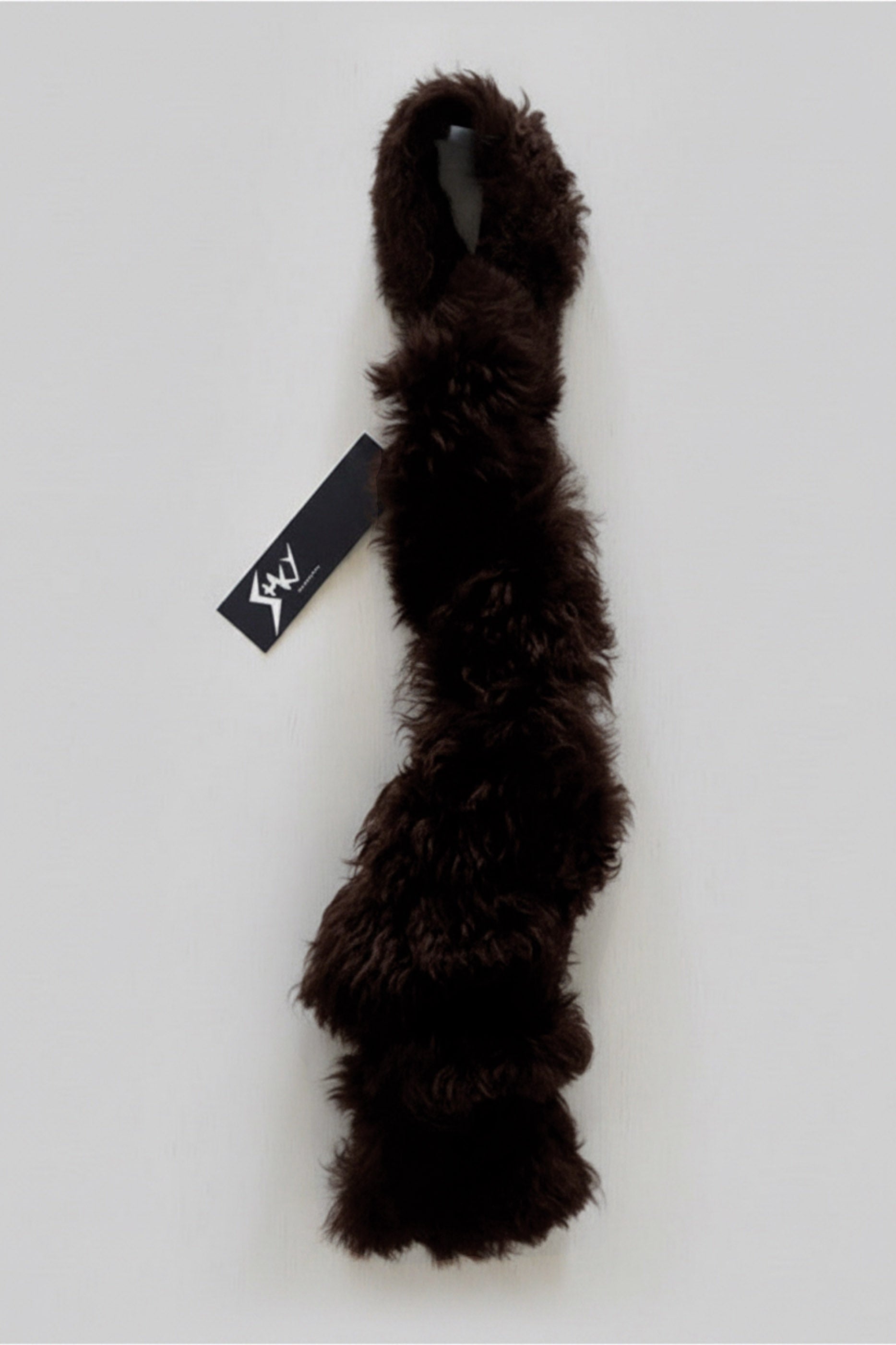 Stacy Stewart Smith Espresso Shearling & Leather Coil Scarf fur side with Stacy Couture hang tag against gray backdrop.