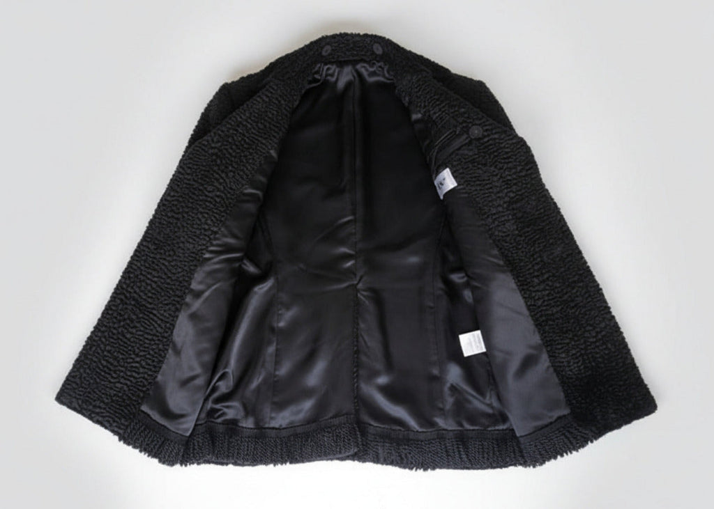 Stacy Stewart Smith Men's Black Knight Faux Persian Lamb Coat in Coal Black, shown open on flat surface revealing lining details.