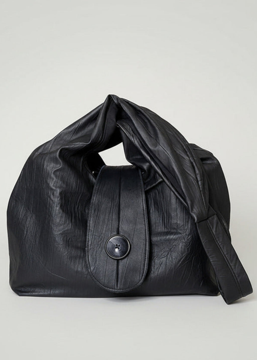 Stacy Stewart Smith Euclidean Space Crinkled Leather Messenger Bag with handle down on a white surface and backdrop.