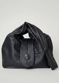 Stacy Stewart Smith Euclidean Space Crinkled Leather Messenger Bag with handle down on a white surface and backdrop.