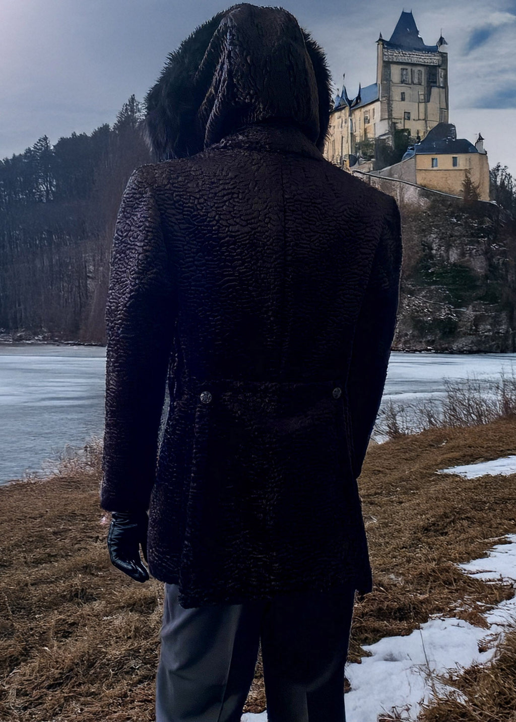 Stacy Stewart Smith Men's Black Knight Faux Persian Lamb Coat in Coal Black, back view shown on mannequin at 6'3 facing a moated castle landscape