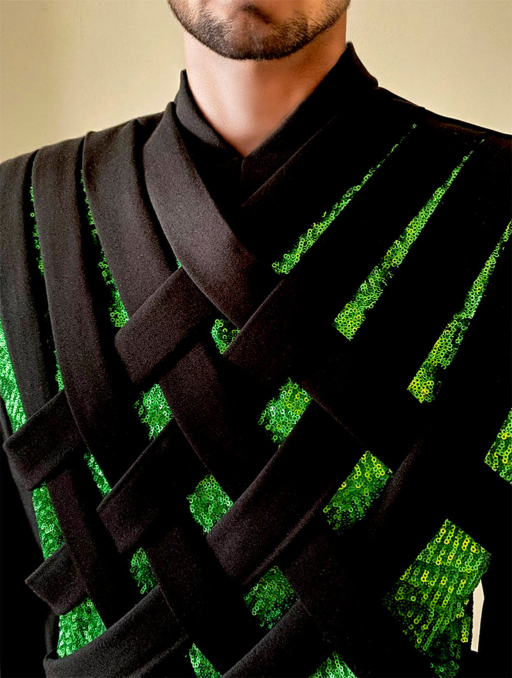 Front zoomed view of a mannequin 6'3" wearing a Stacy Stewart Smith Men's Argyle Labyrinth Peridot and Black Sequined Knit Top against an Antique White wall. 