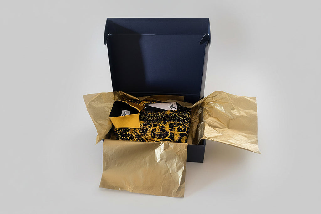 Stacy Stewart Smith Men's Pawns in Gold on Black Hand-Painted Premium Cotton Percale Dress Shirt folded in a black luxury gift box with gold metallic tissue paper.