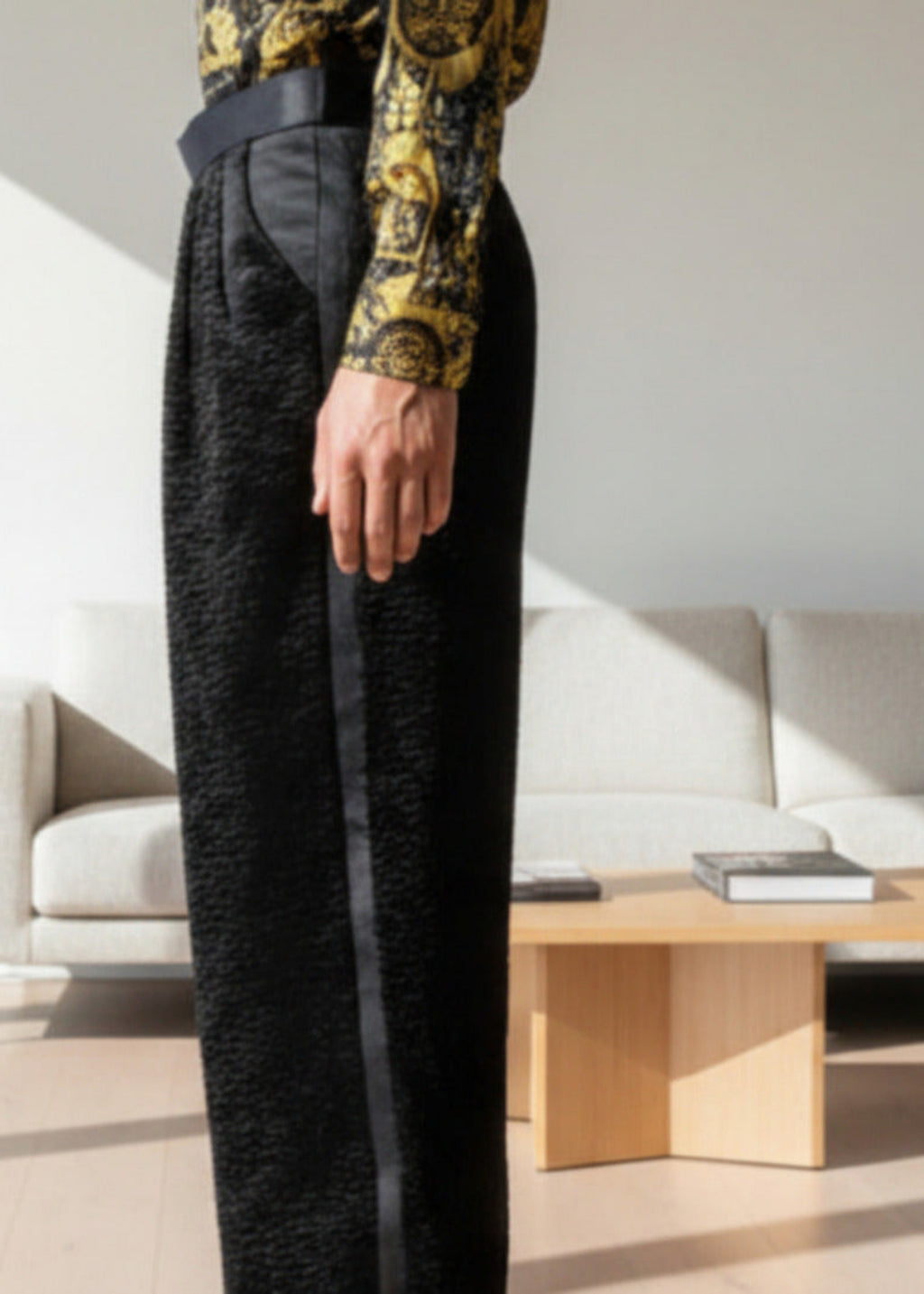 Stacy Stewart Smith Men's Faux Persian lamb pleated Windsor pants, shown on mannequin at 6'3 from side view in a room with an ivory sofa, wood floor and cocktail table. .