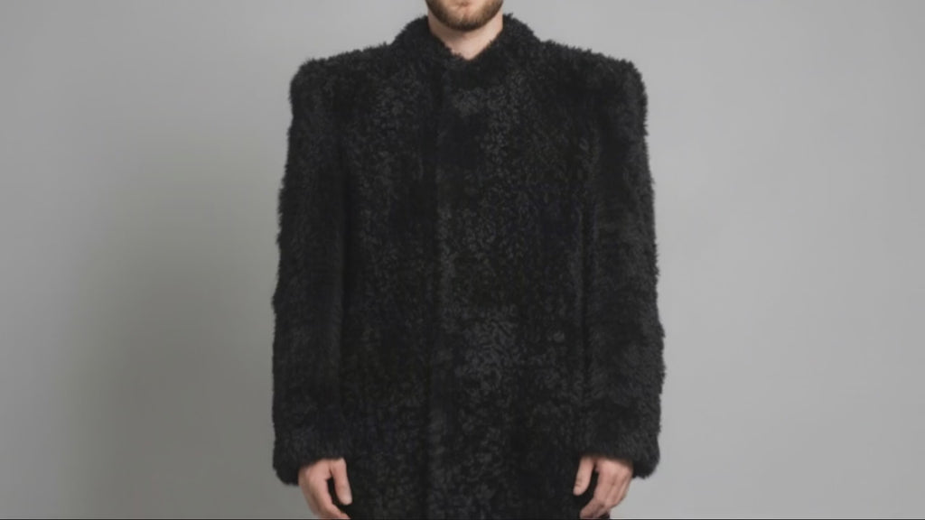 Man wearing the black Bishop Tigrado shearling coat opens the front to reveal its satin lining, interior pockets, and a hand-painted shirt.